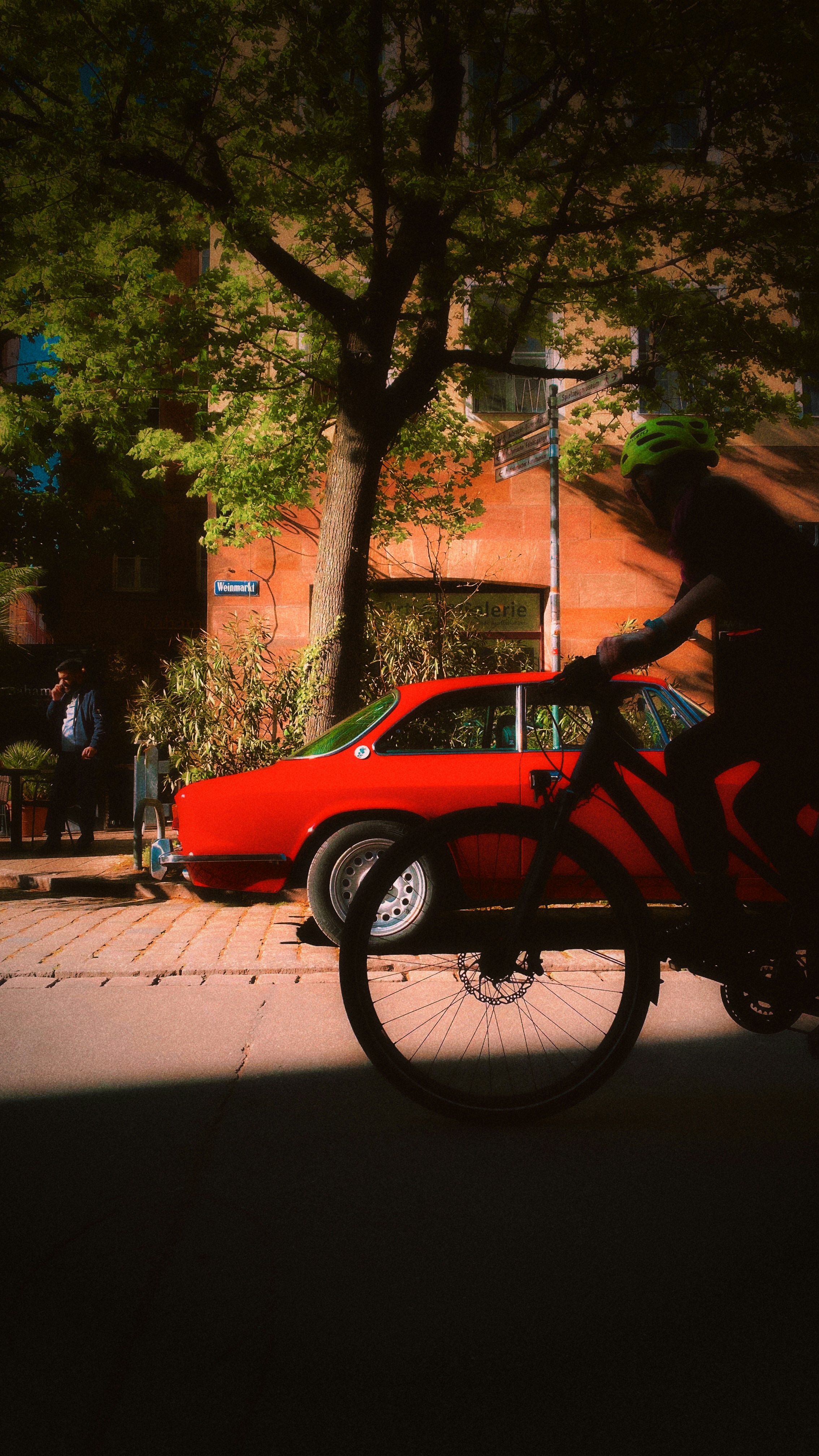 Ciclista supera un'auto rossa su strada soleggiata