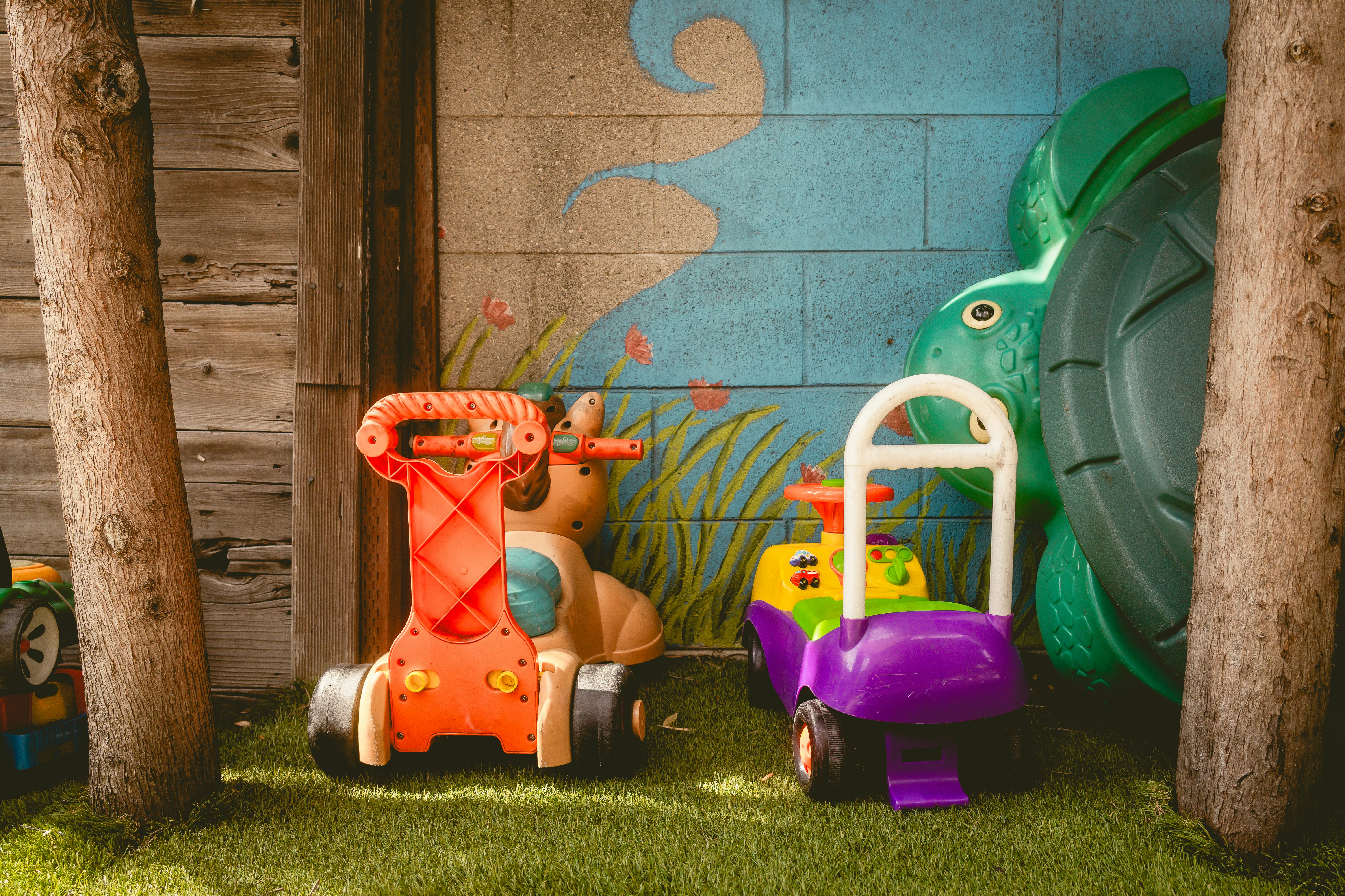 Two colorful ride-on toys in a grassy area.