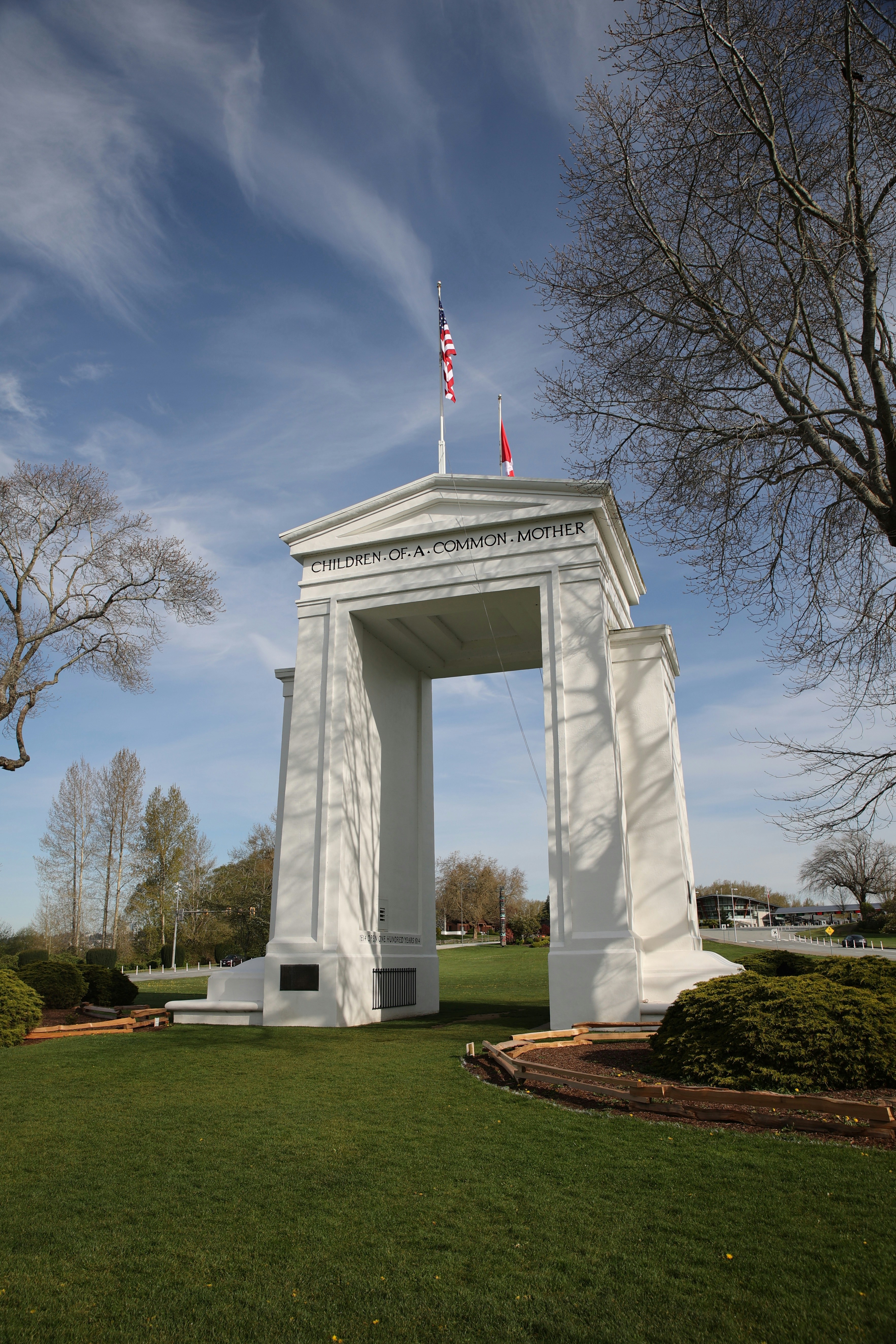 Monument en arc blanc avec drapeaux sous un ciel bleu