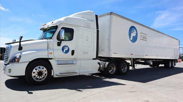 A white semi-truck with a blue logo parked outside.
