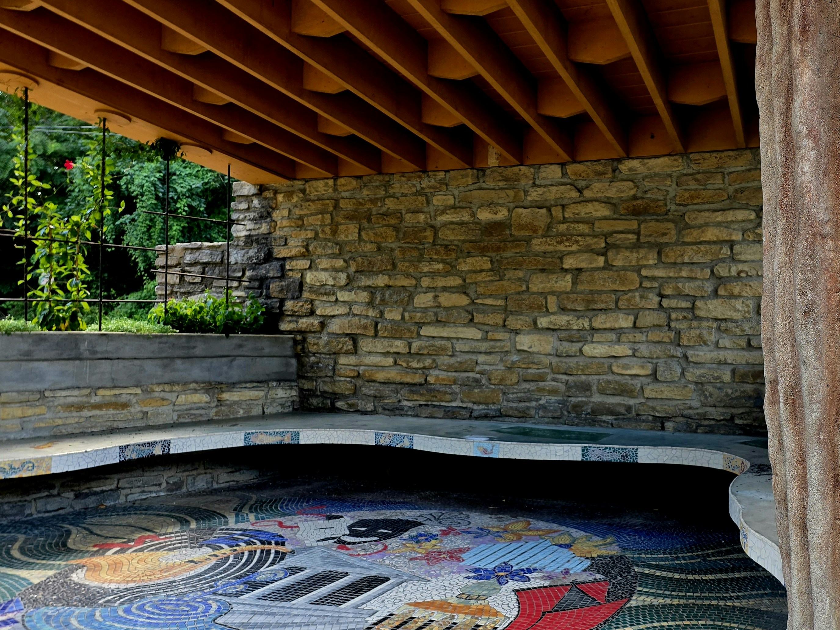 Stone wall and mosaic pool under wooden roof