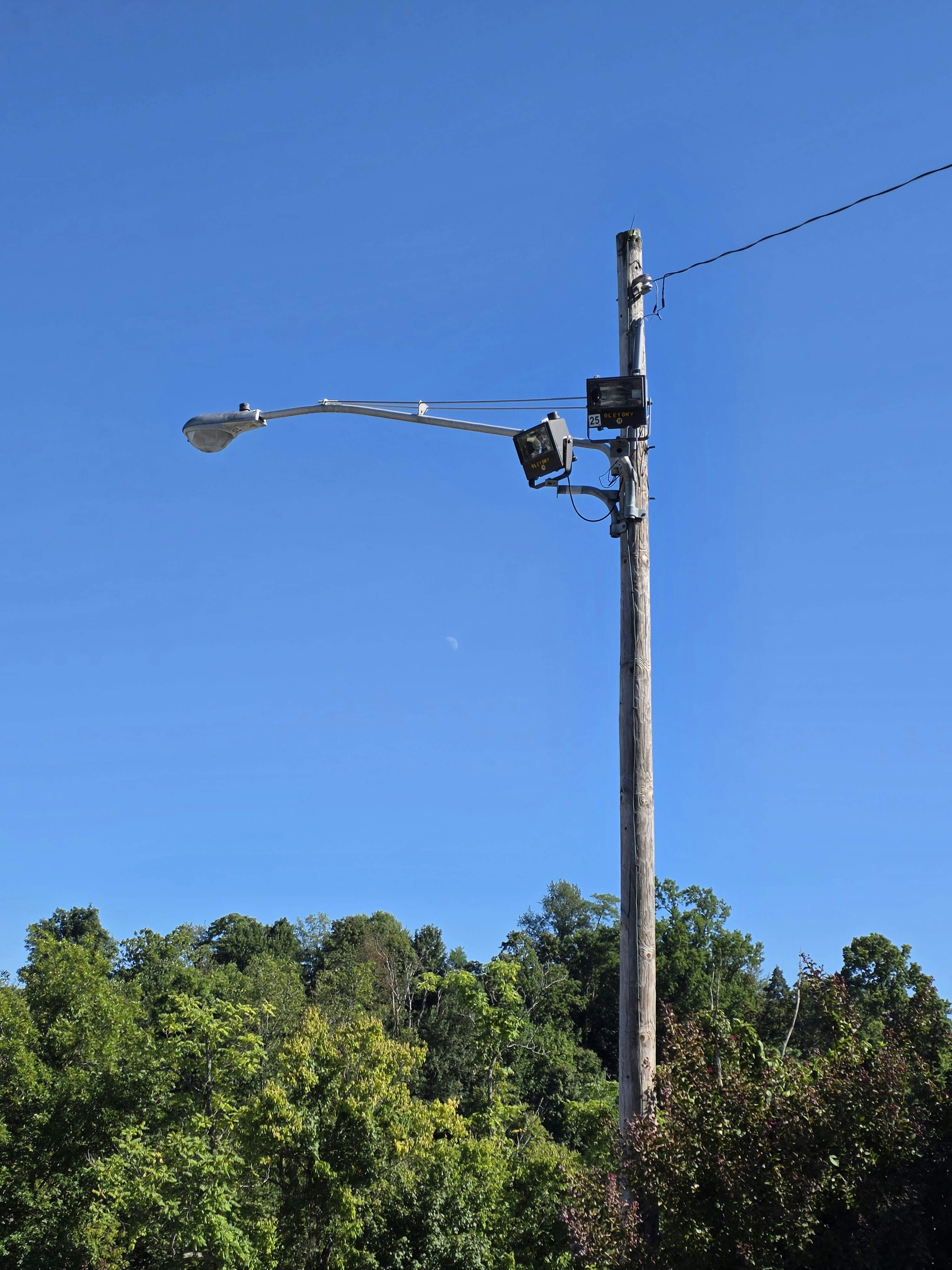 Street light pole with multiple fixtures against blue sky.