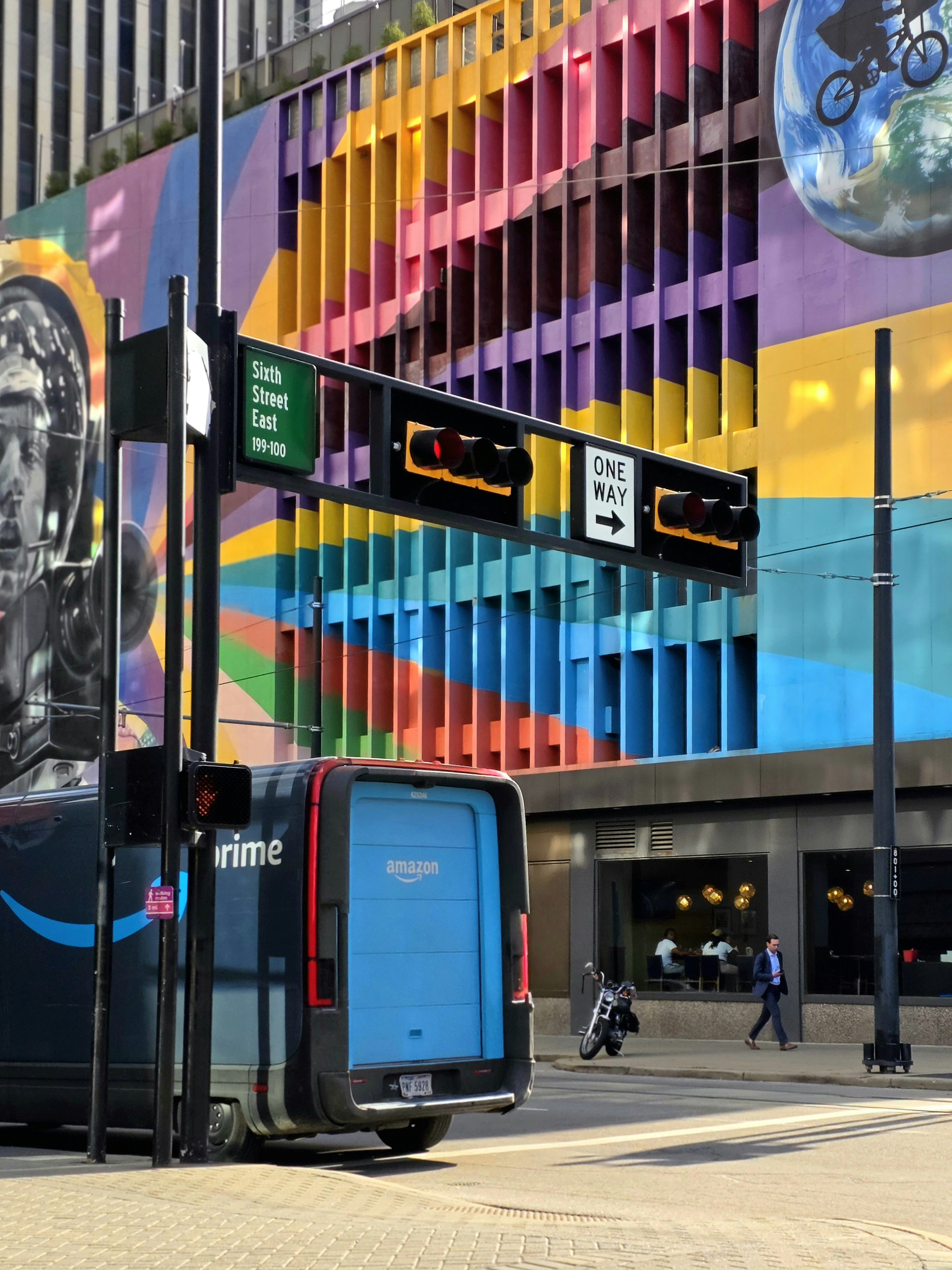 Amazon van parked near colorful mural and modern buildings.