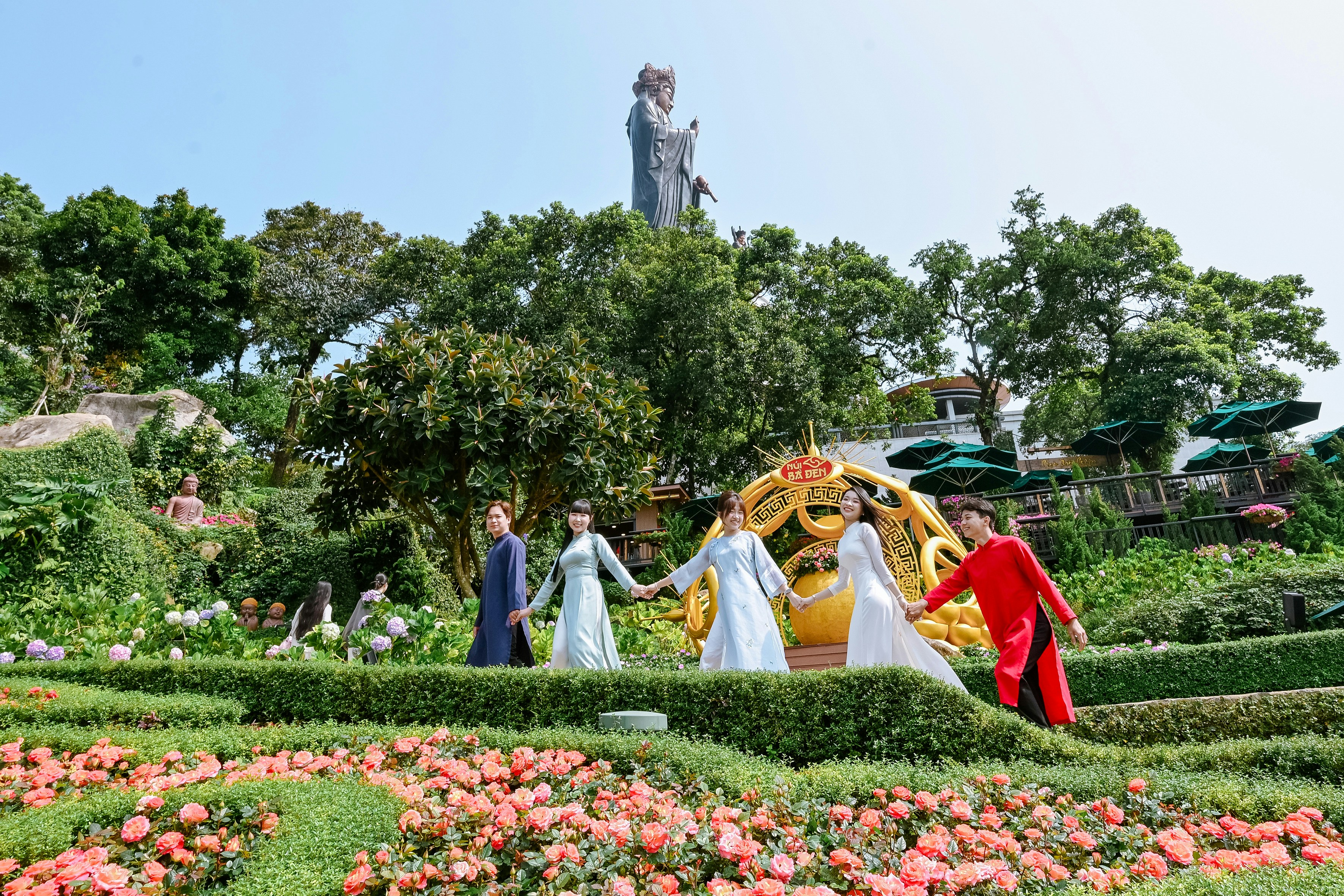 Pessoas com roupas tradicionais de mãos dadas em um jardim