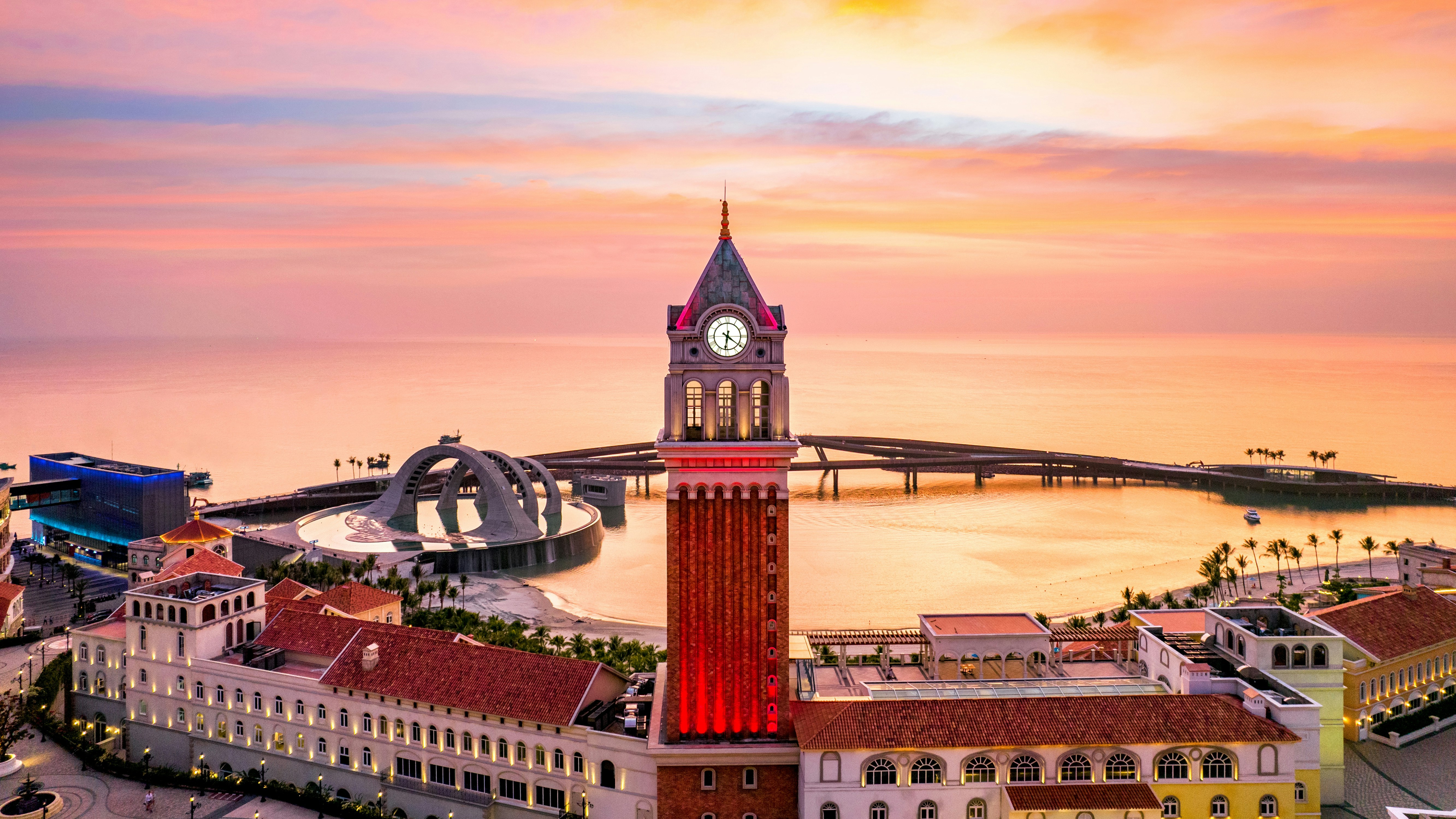 Edifícios em estilo italiano com uma torre de relógio ao pôr do sol.