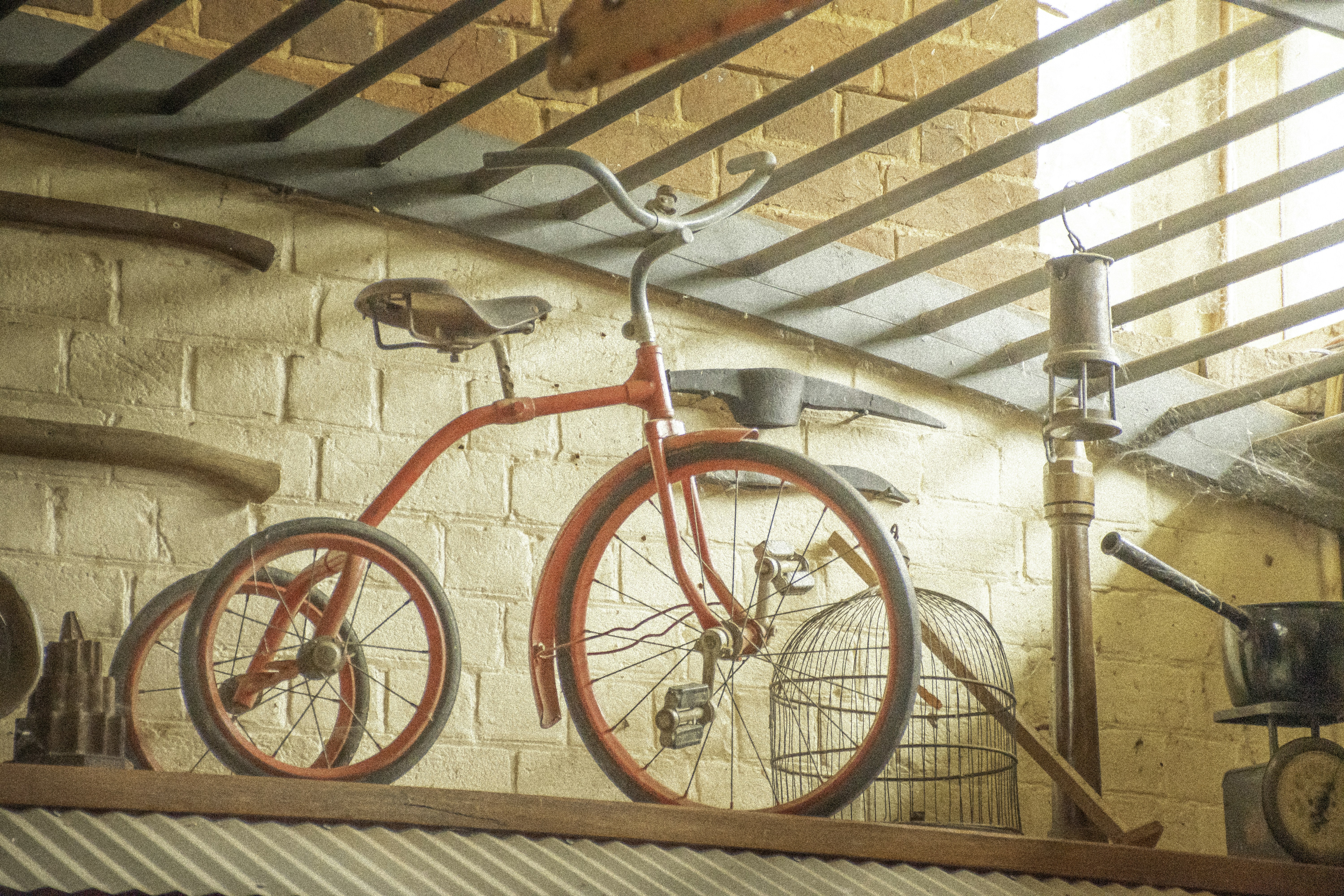 Un tricycle rouge vintage repose sur une étagère.