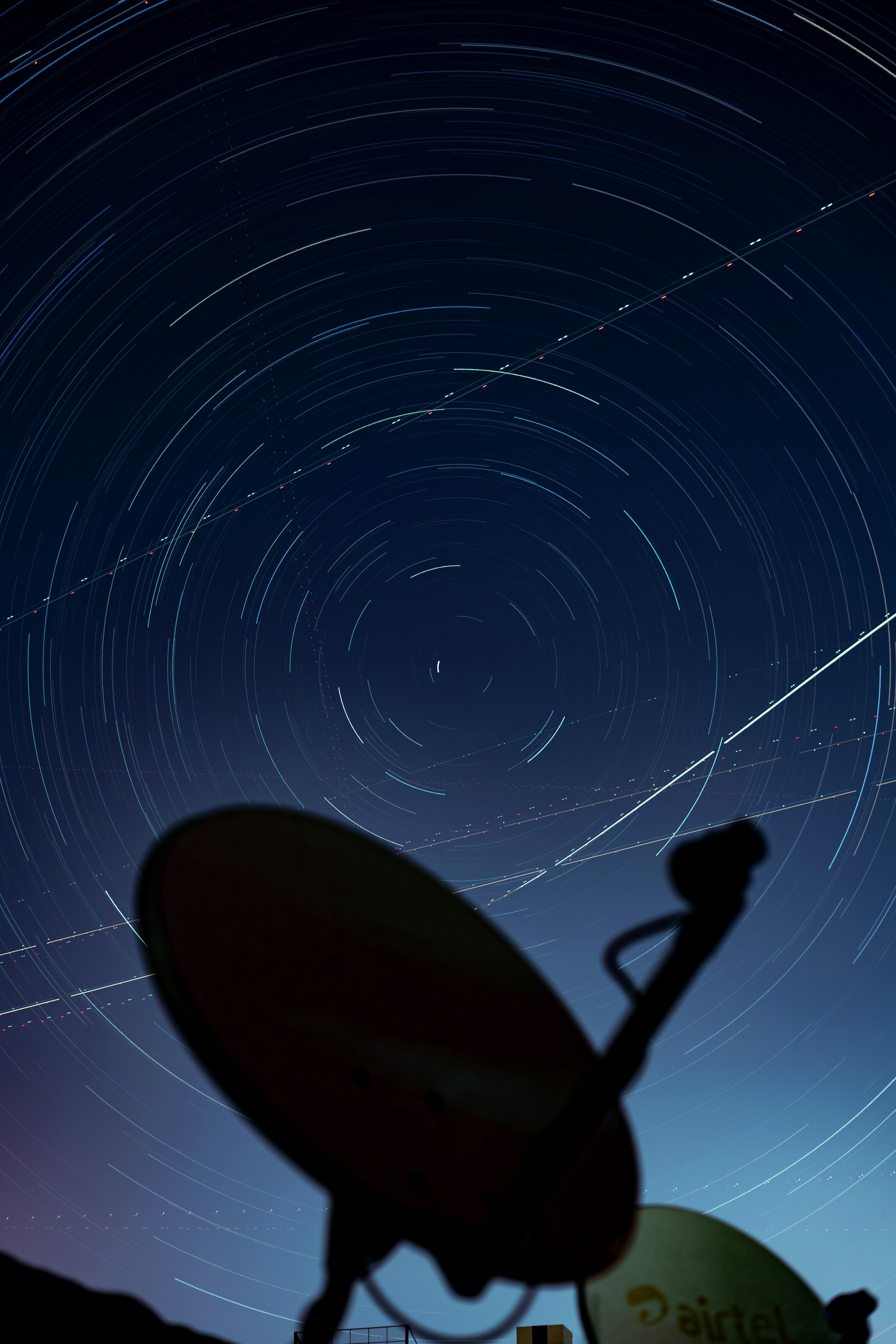 Star trails over a satellite dish at night