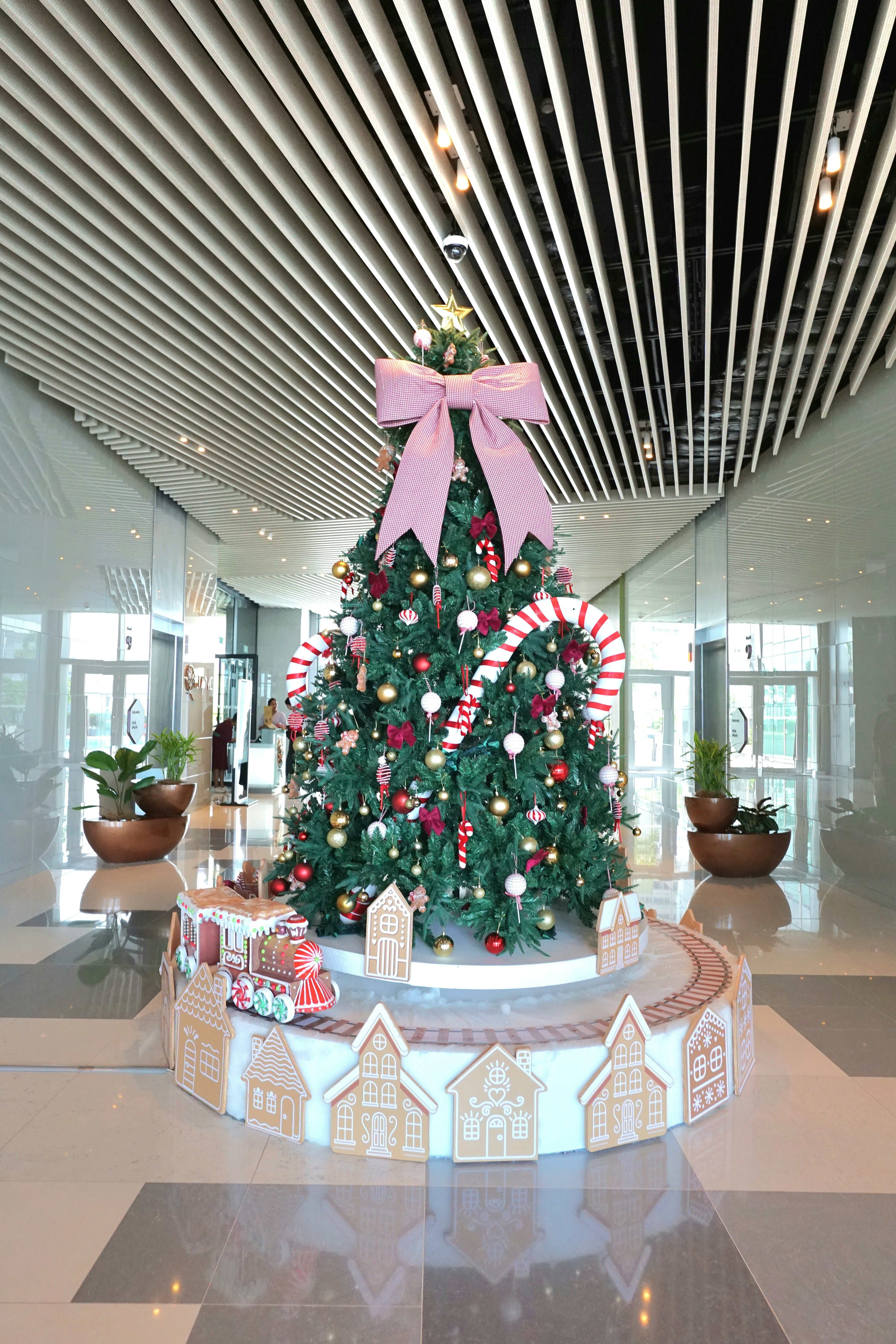 A decorated christmas tree with a train and gingerbread houses.