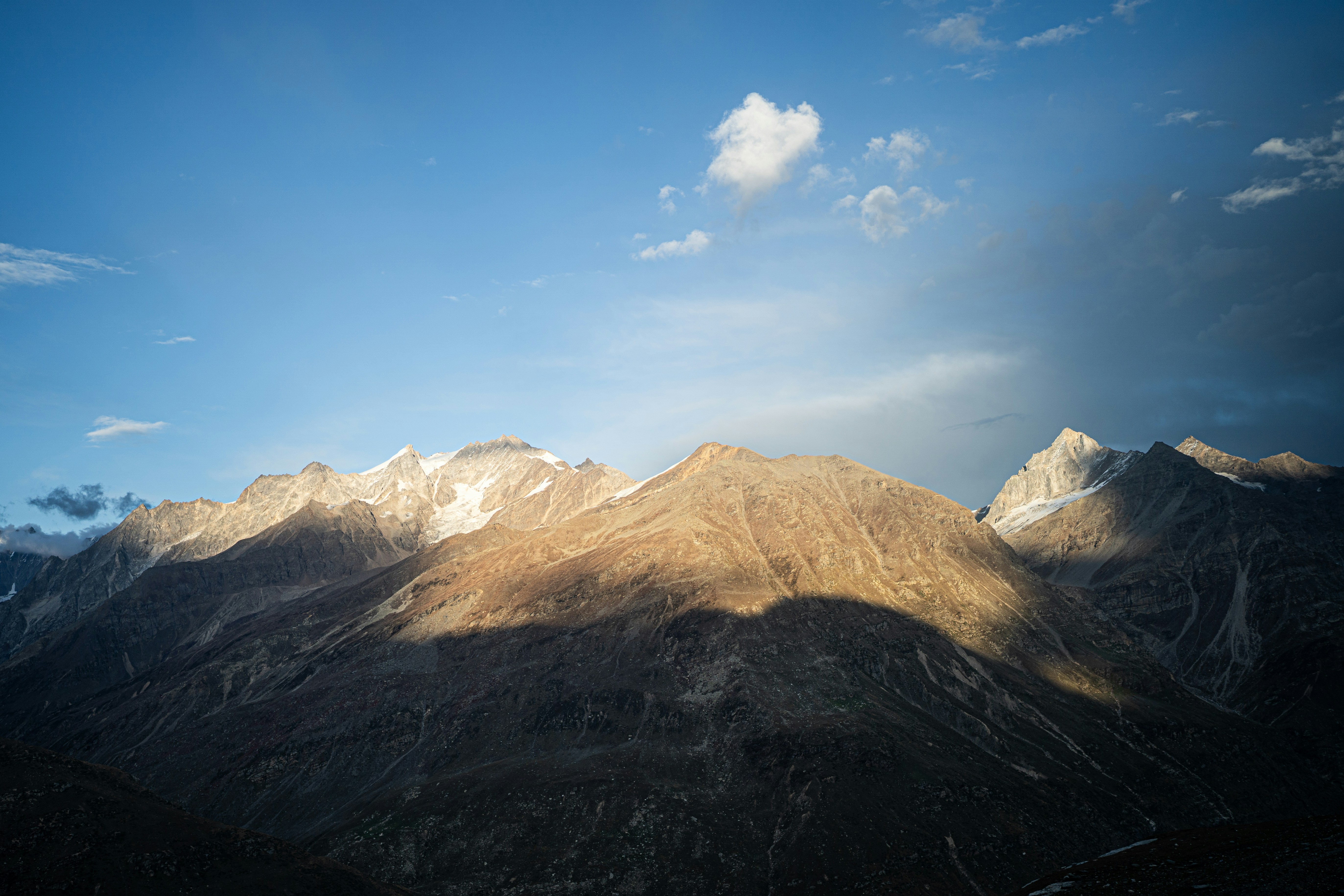 Sunlit mountain range under a blue sky