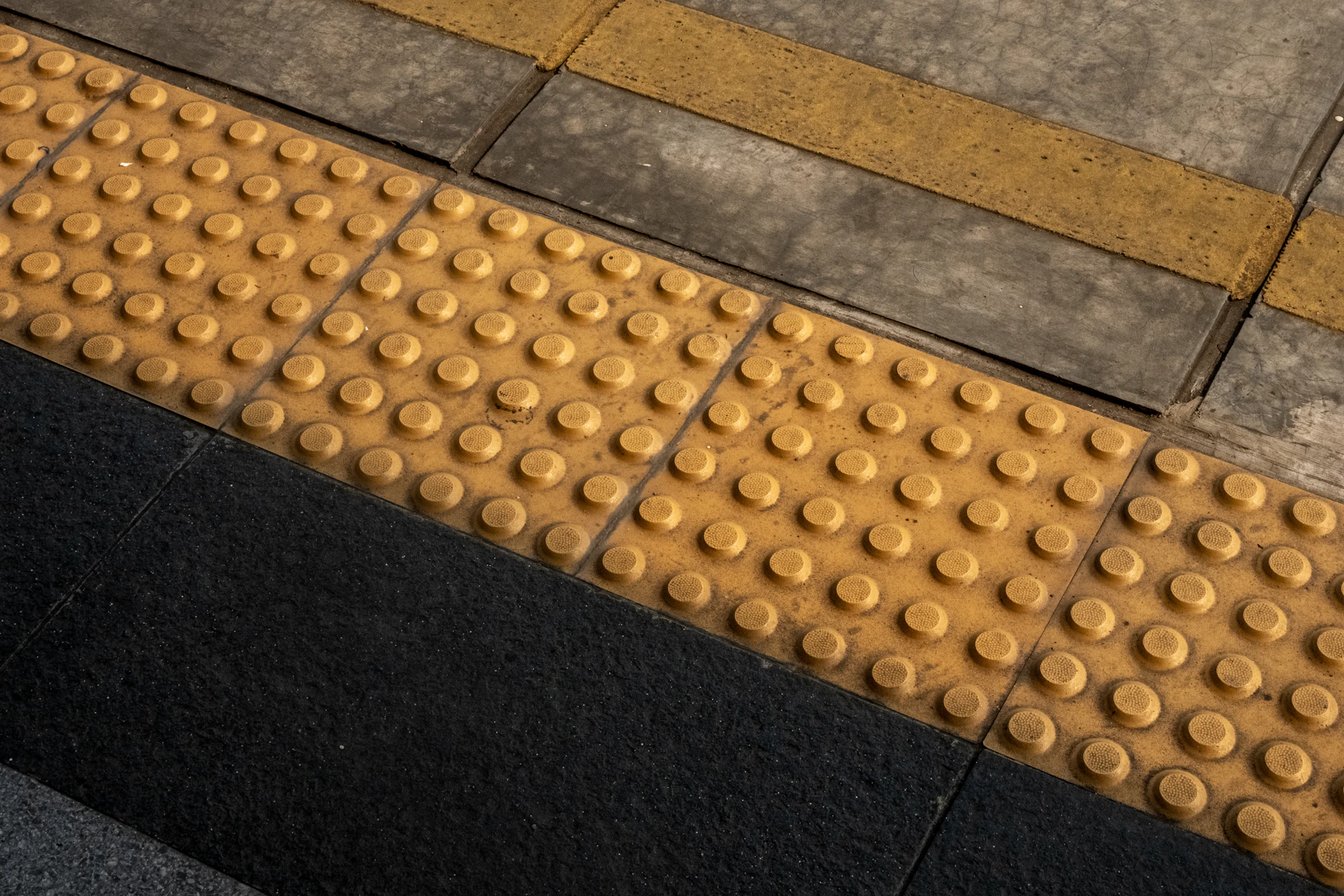 Tactile paving with raised dots on a sidewalk.