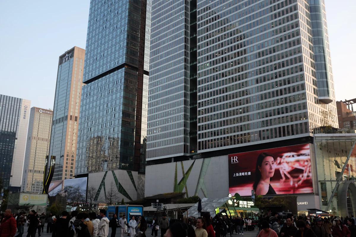Large outdoor advertising displays above a busy city road and commercial buildings