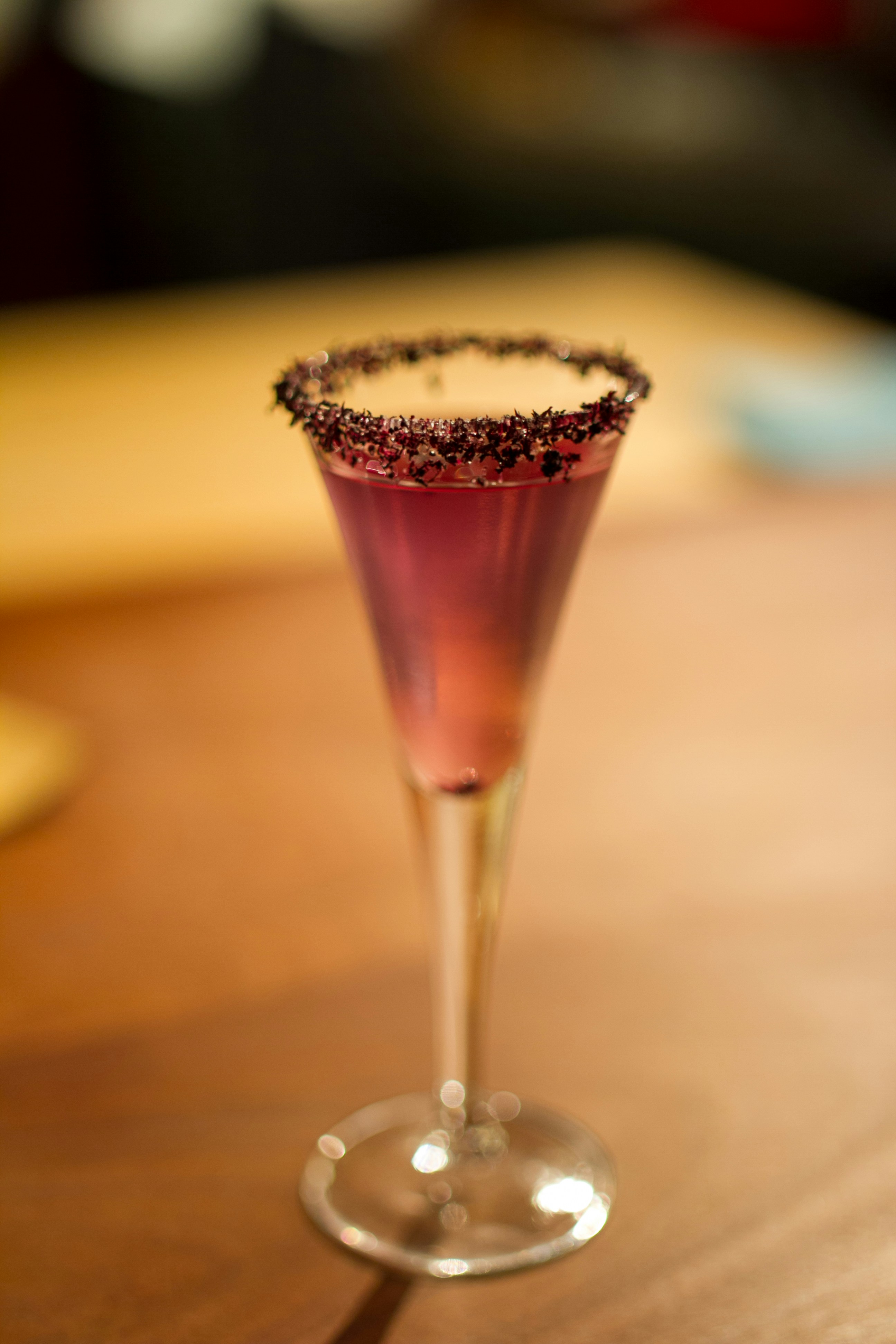 A tall glass with a purple drink and dark rim