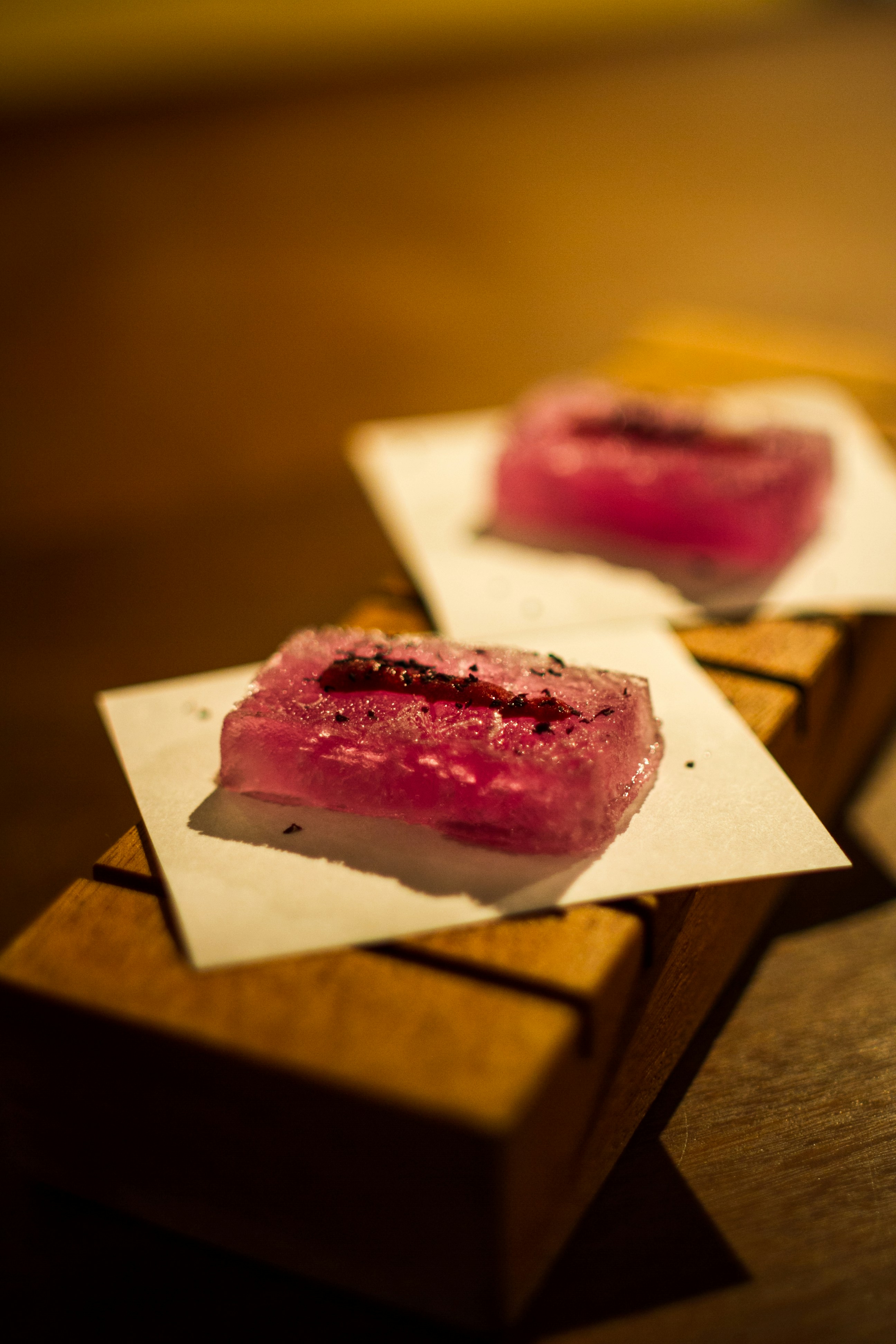 Two pink translucent cubes topped with seeds