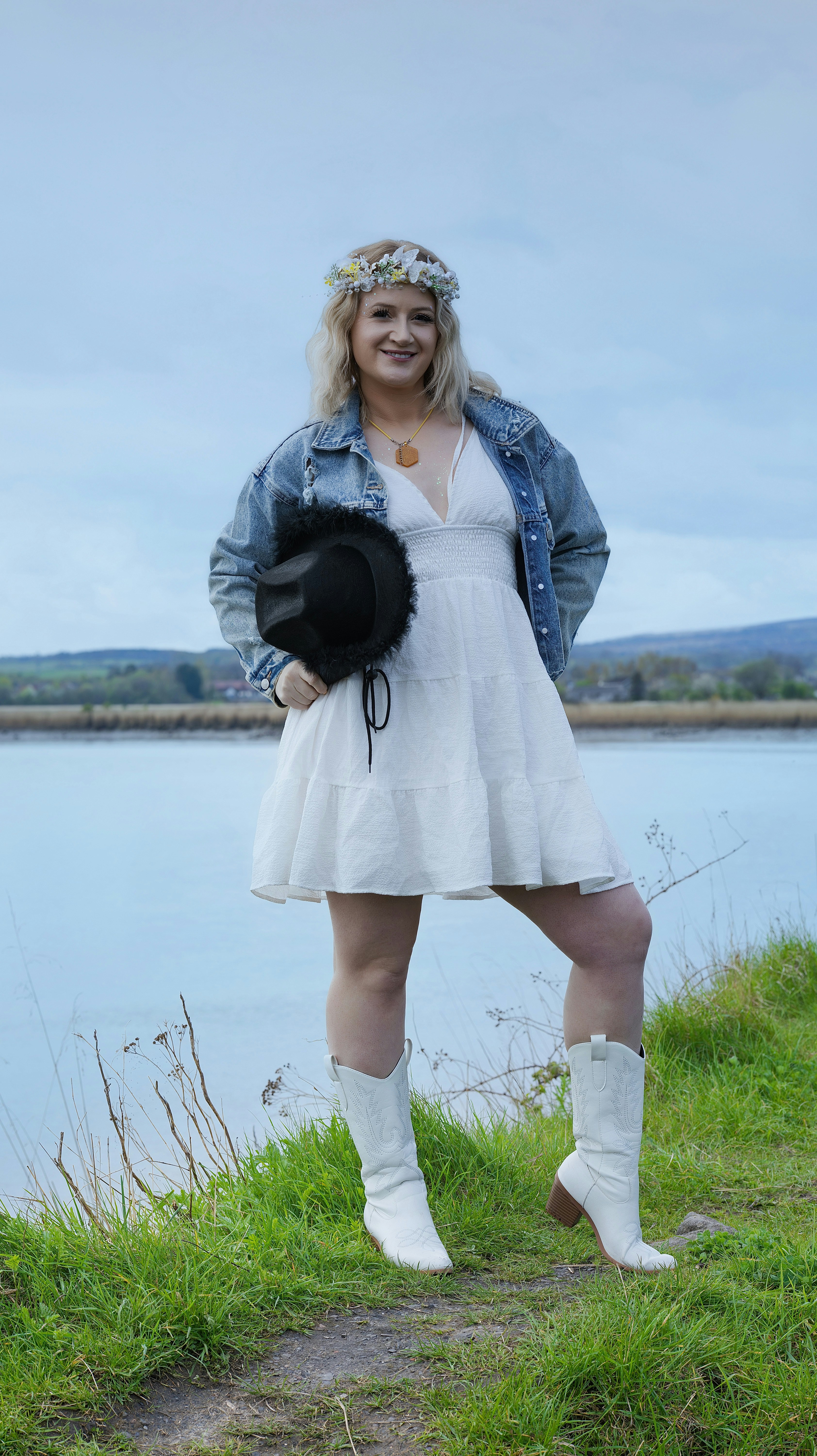 Woman in white dress and cowboy boots by the water