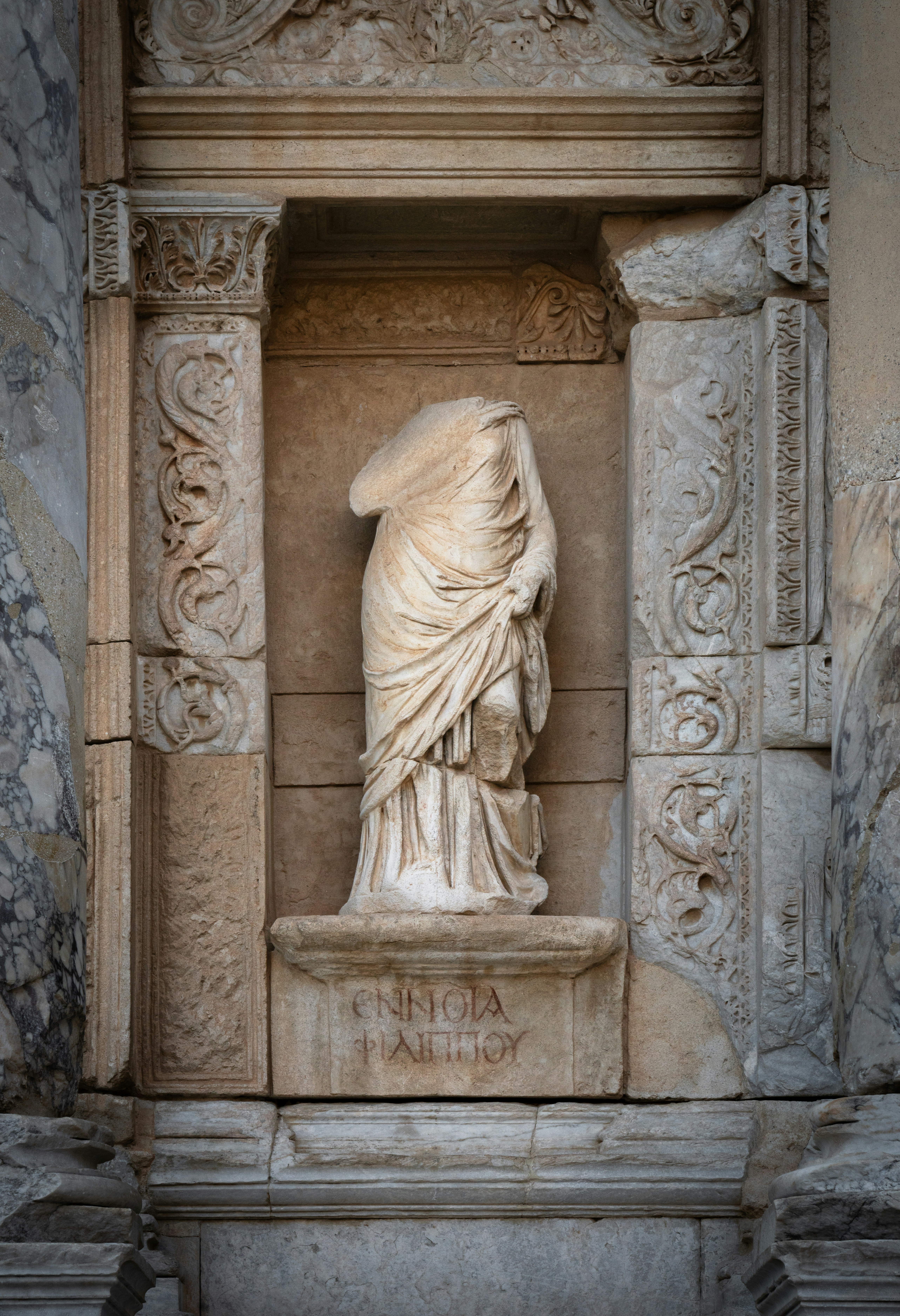 Antica statua decapitata in marmo in una nicchia di pietra ornata