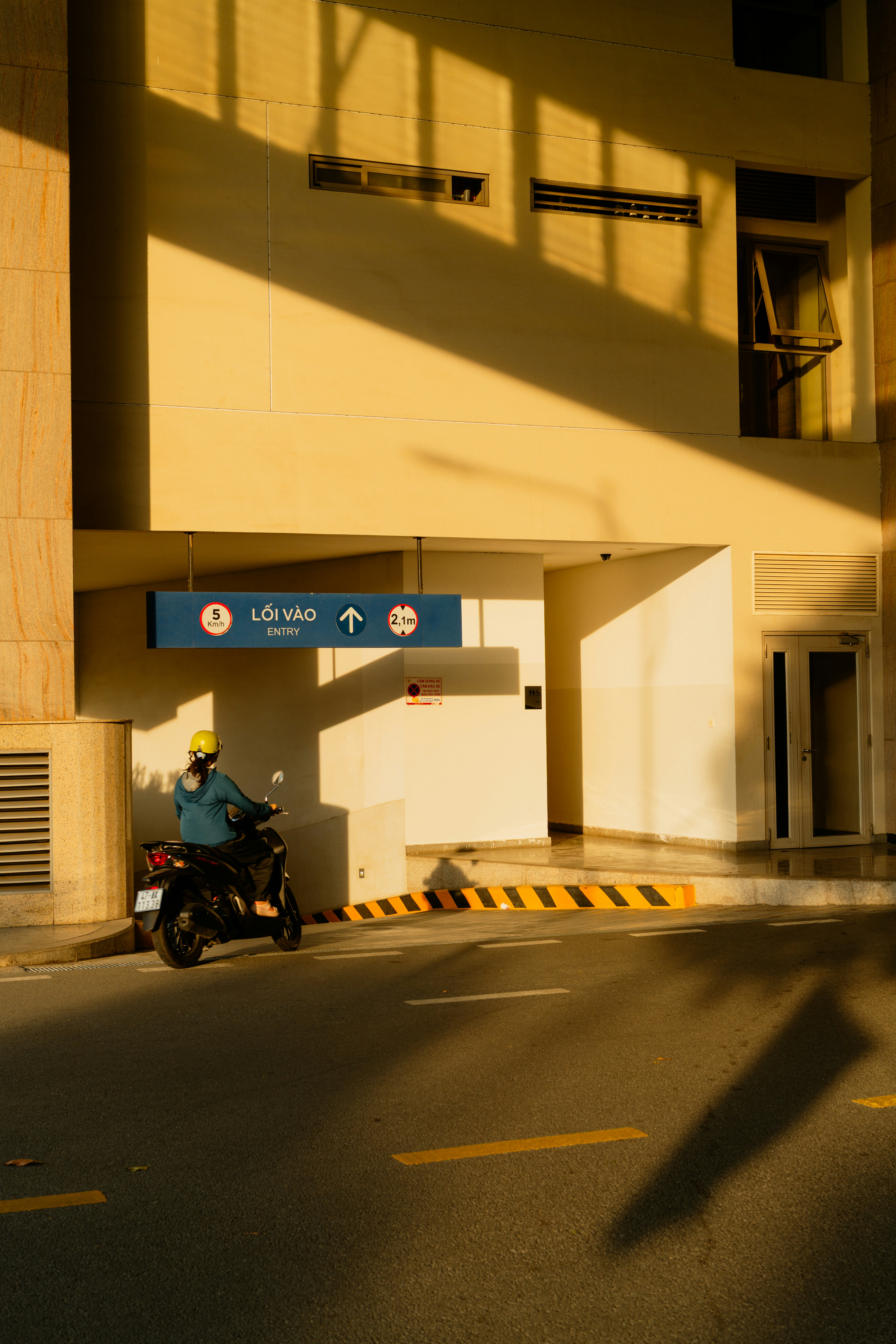 Un cycliste en scooter garé près de l’entrée du bâtiment