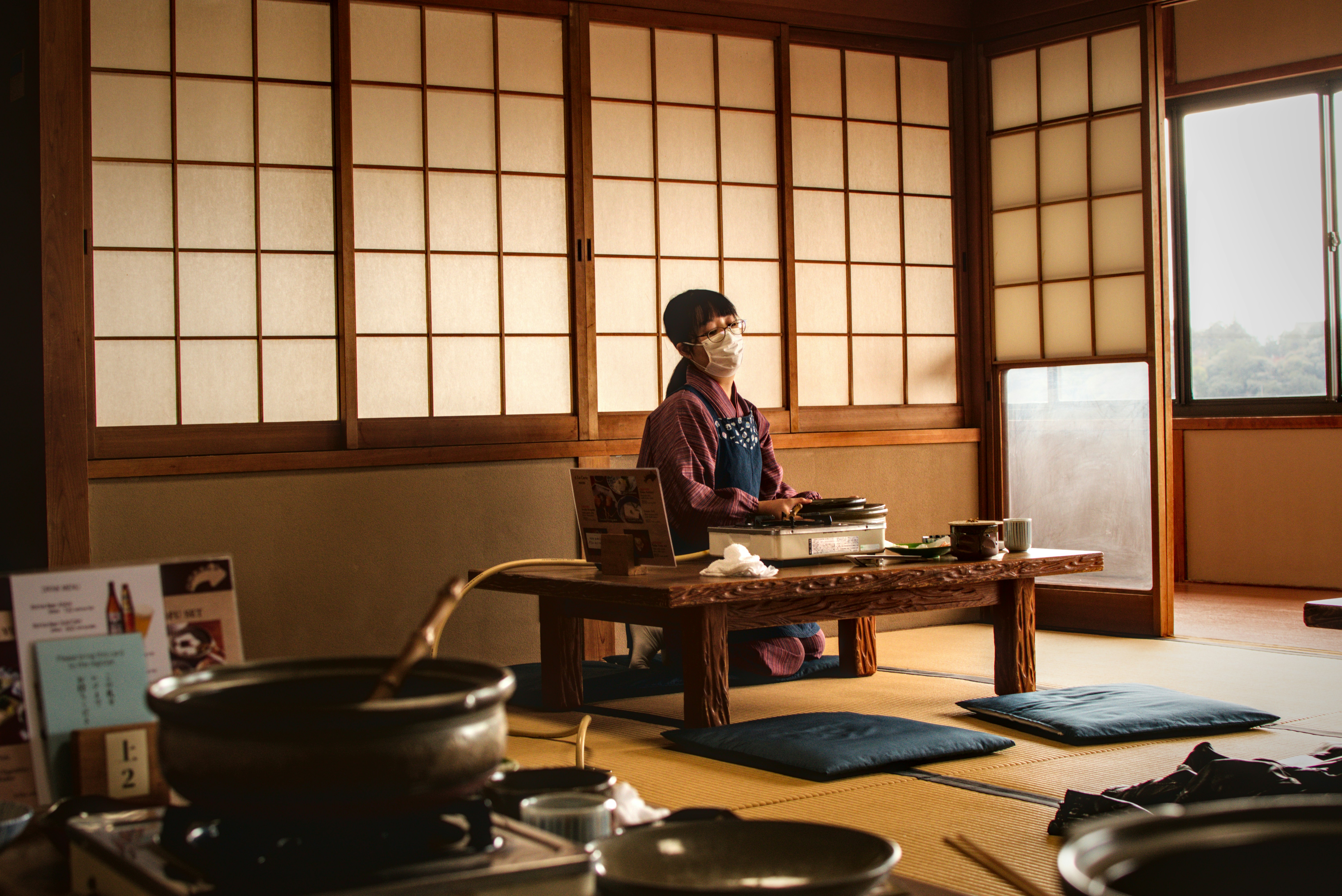 Hombre preparando comida en una sala tradicional japonesa.