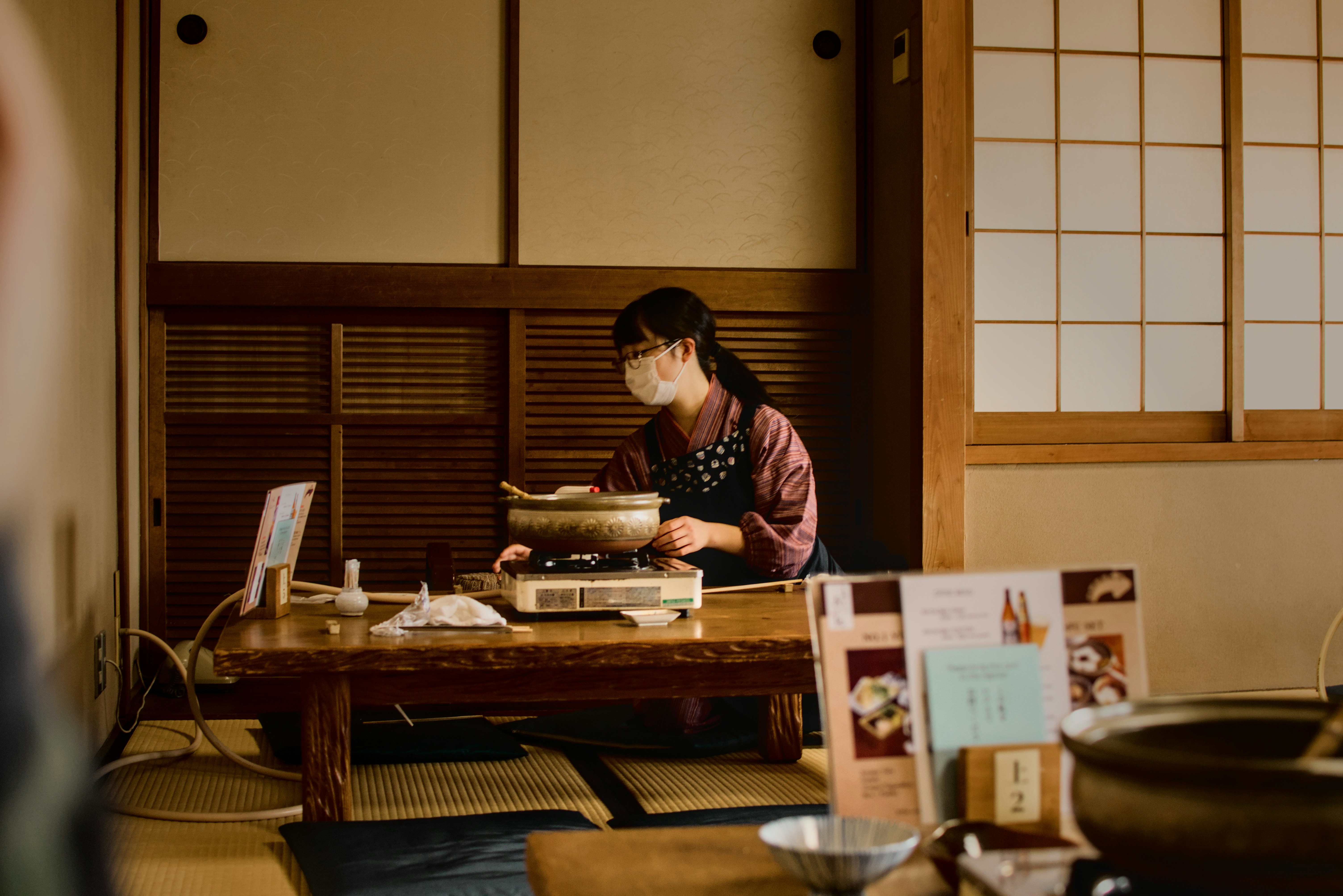 Woman in mask prepares food in traditional japanese room