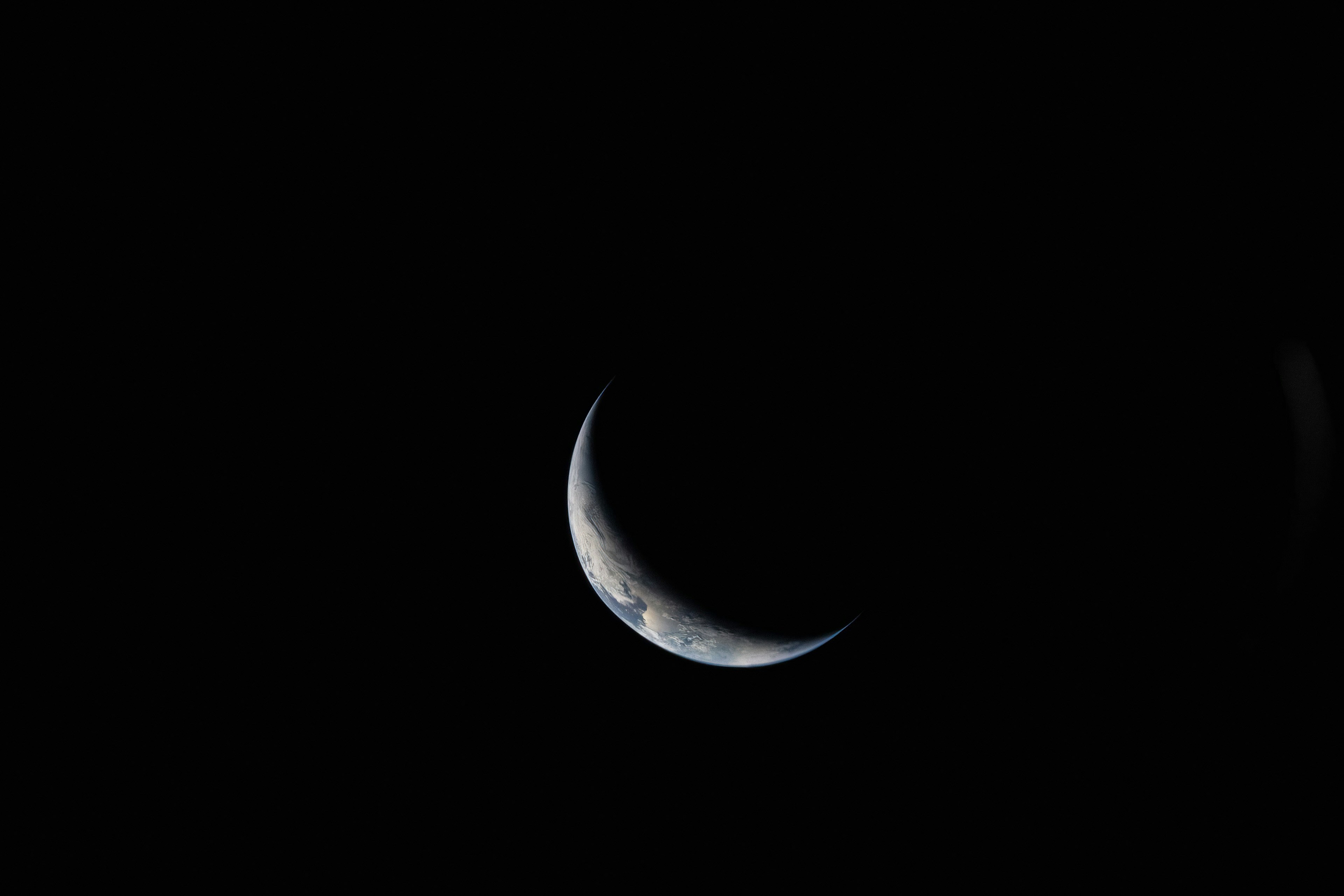 Crescent earth visible in the dark expanse of space