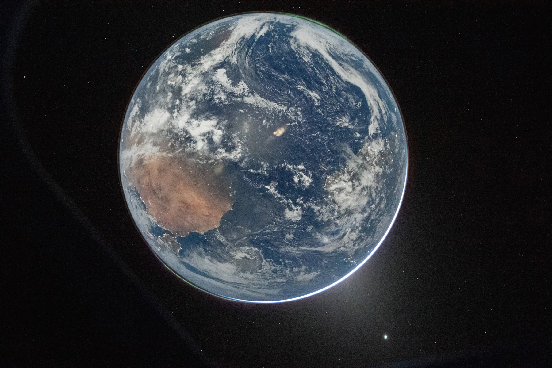 Earth photographed from space at night, city lights and continents visible