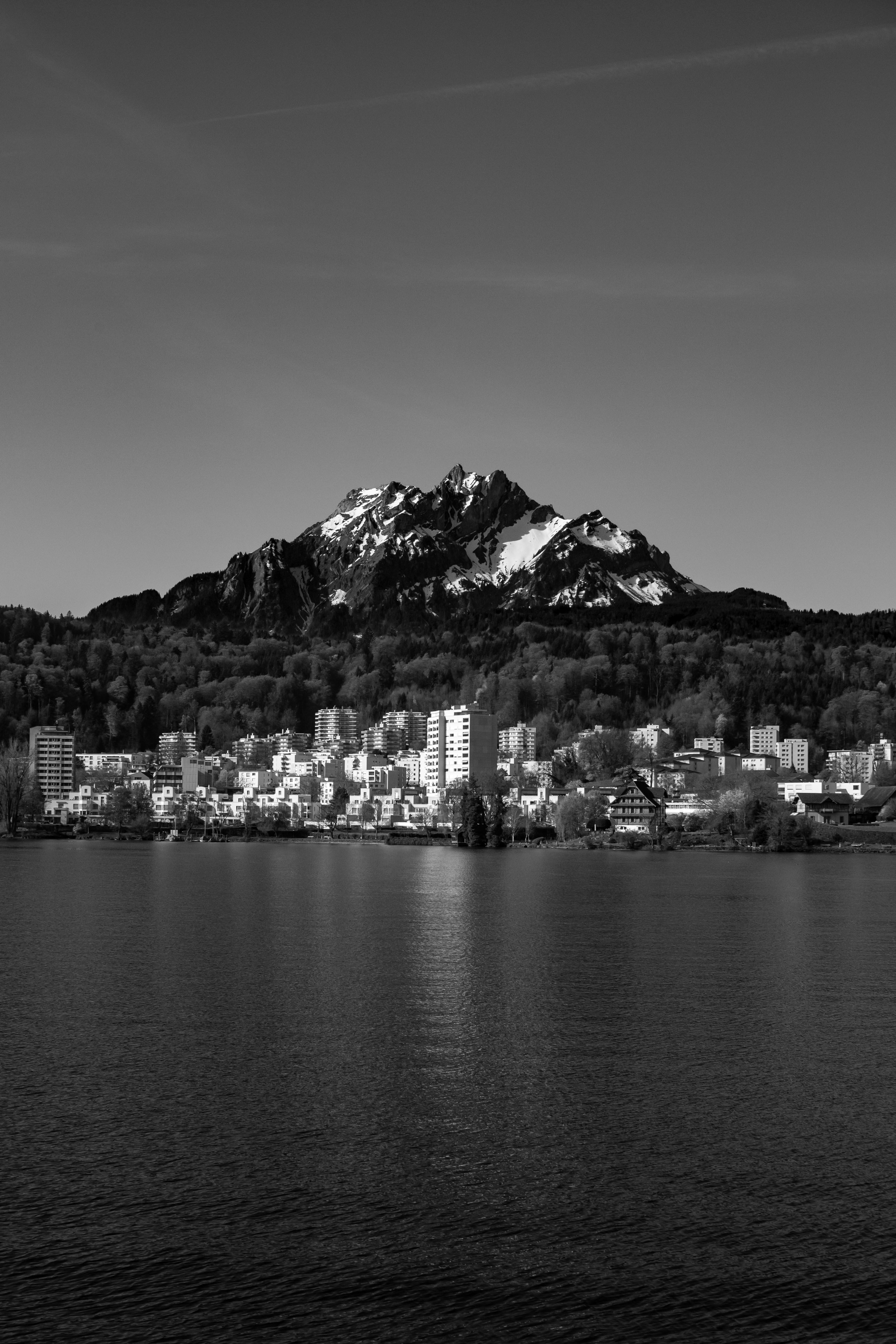 Snow-capped mountain overlooks a city by the water.