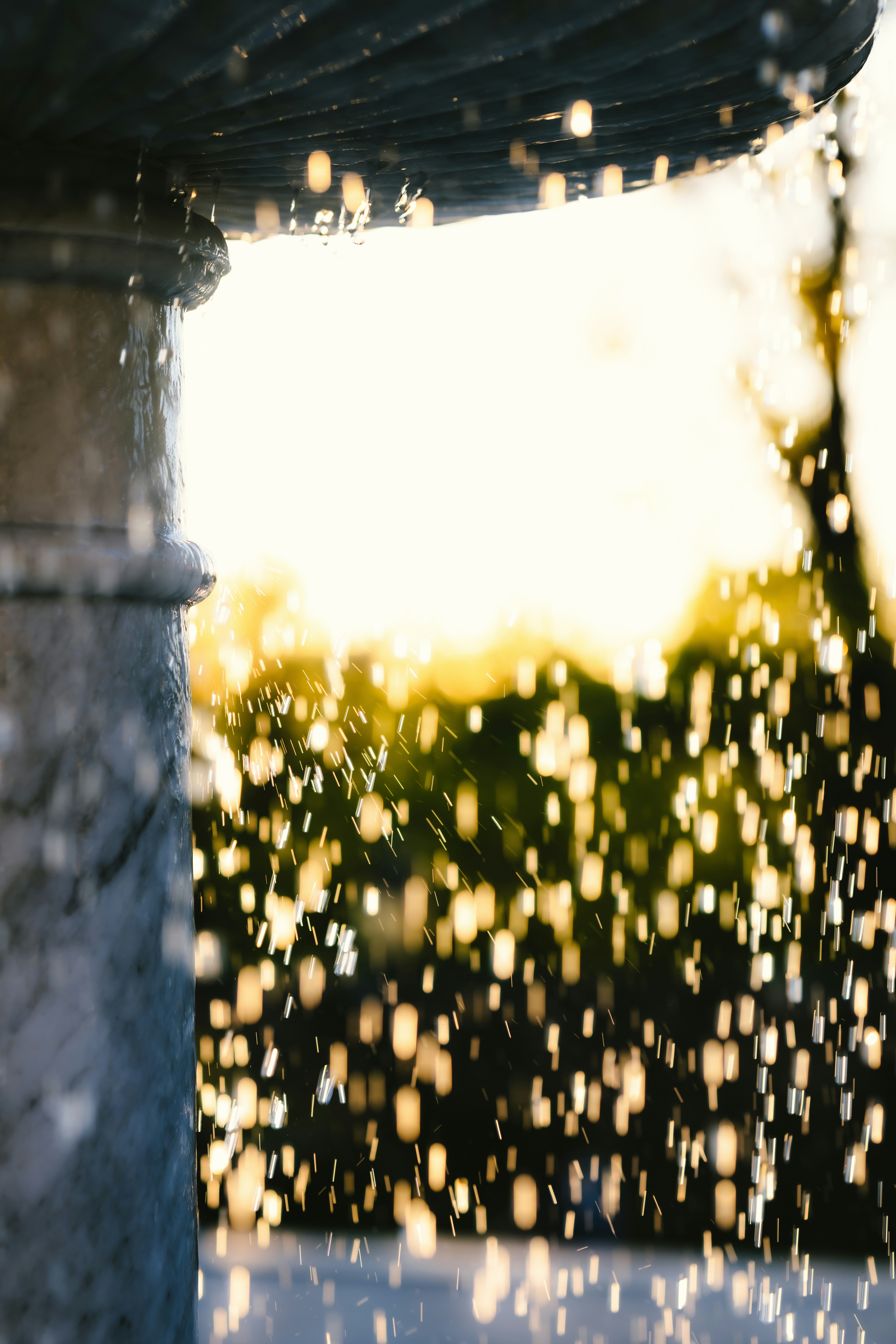 Gocce d'acqua che cadono da una fontana al tramonto.