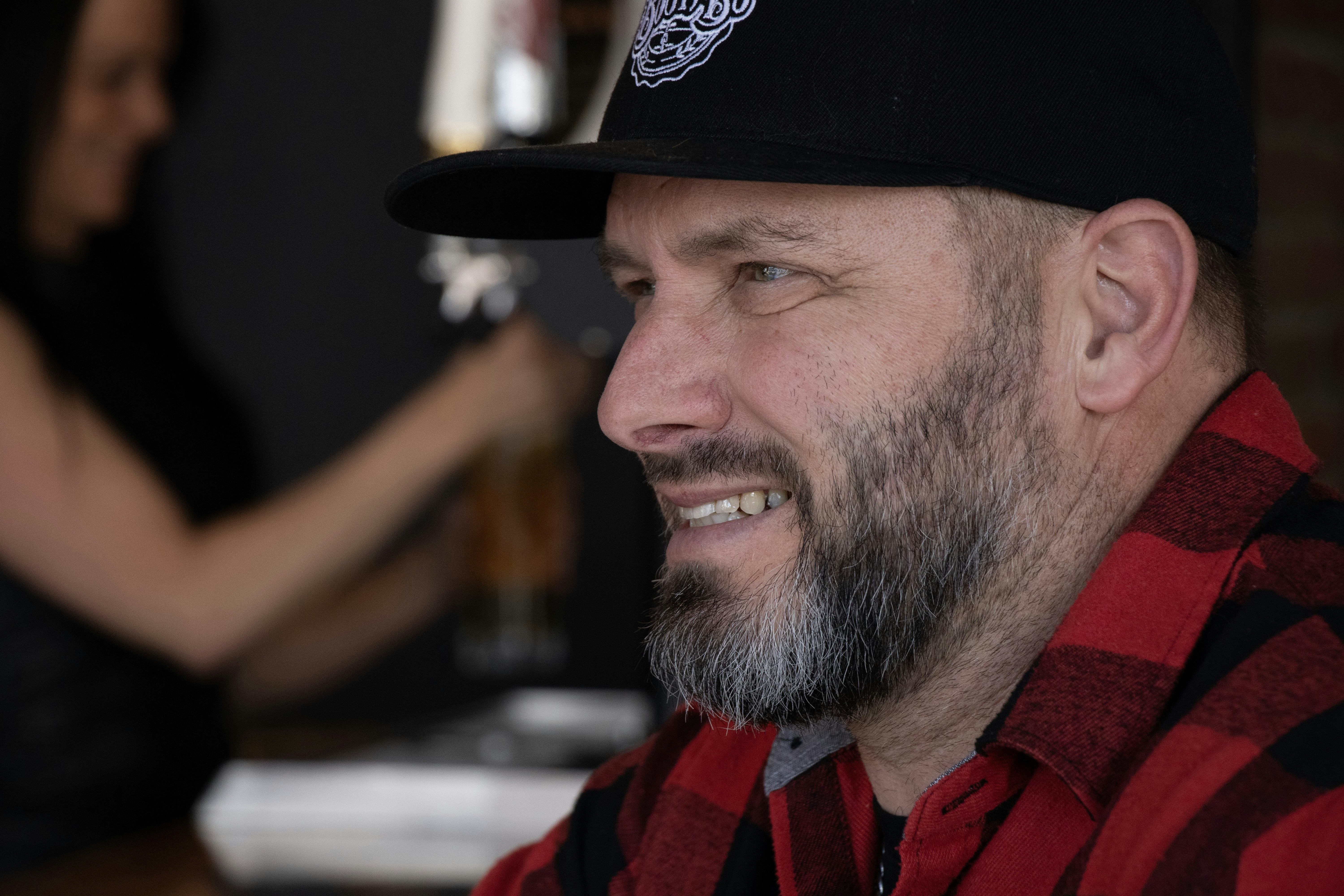 Man with beard wearing a red plaid shirt and hat