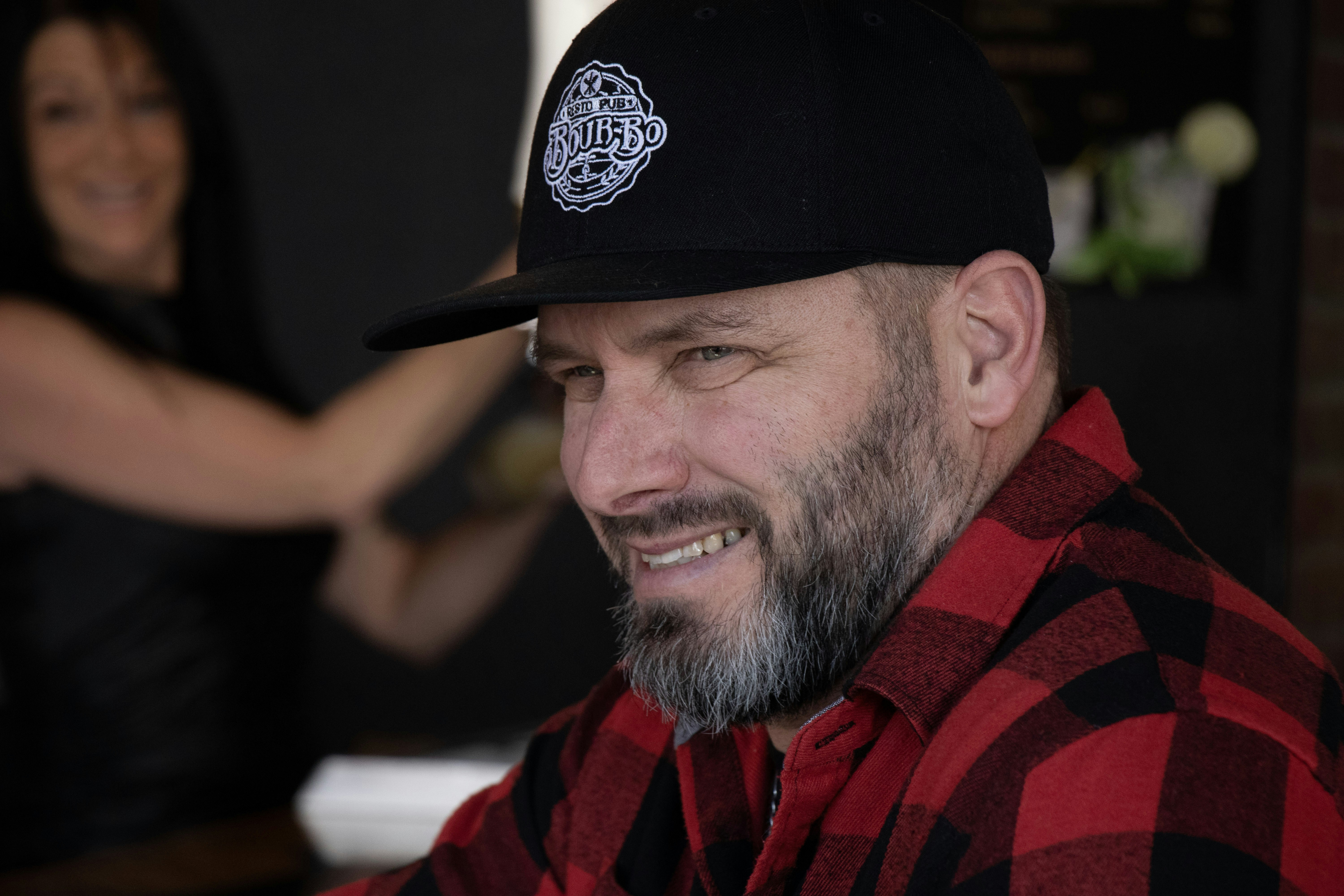 Man with beard and baseball cap smiles