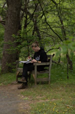 A person sketching on a wooden bench in a forest