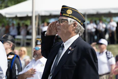 Man in uniform salutes during an outdoor ceremony