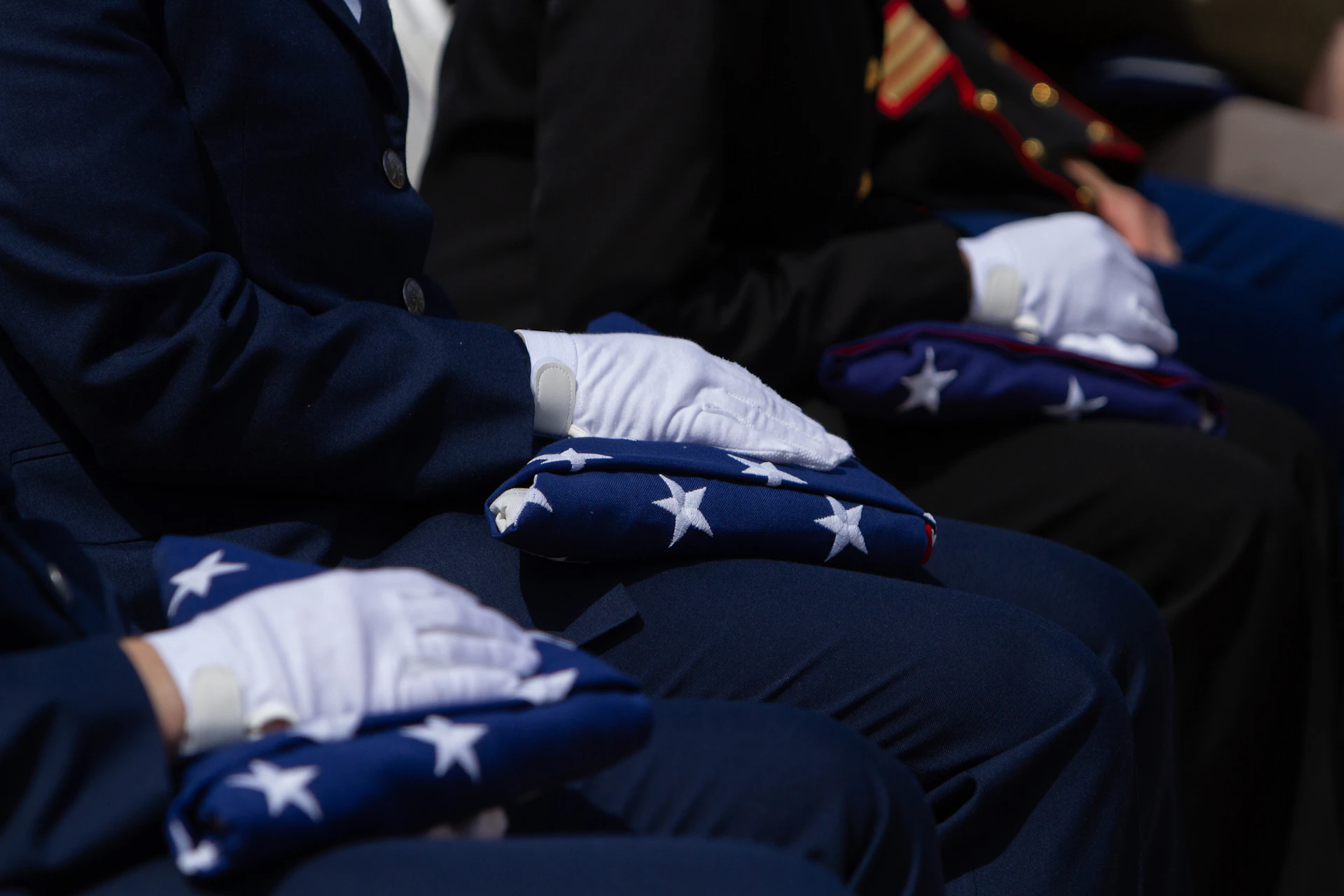 People in uniform carefully fold american flags