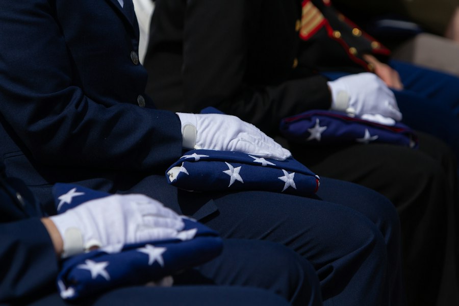 White-gloved honor guard members holding folded American flags