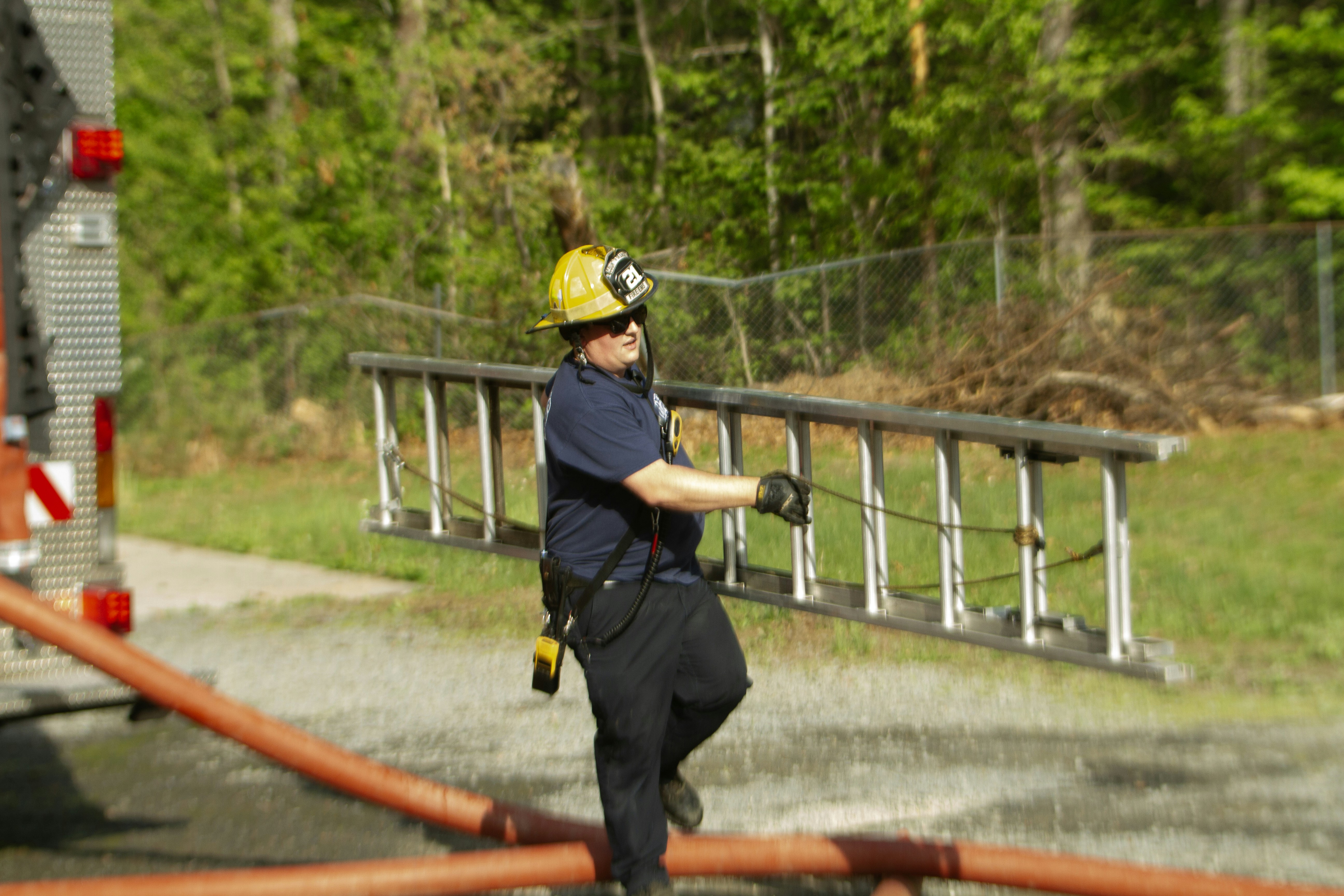 Feuerwehrmann trägt eine Leiter in der Nähe eines Lastwagens