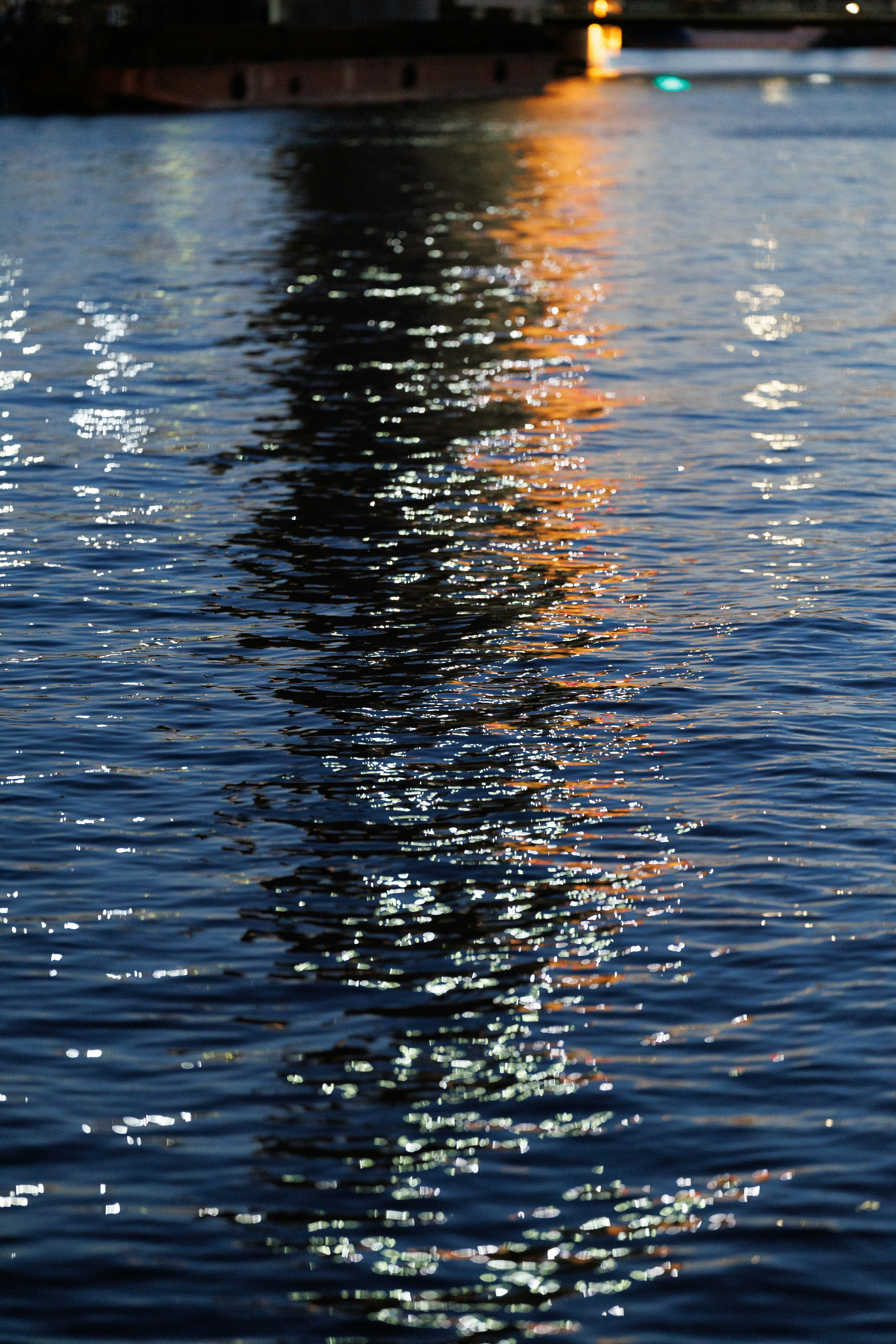 Lichter, die sich auf dunklem, kräuselndem Wasser spiegeln