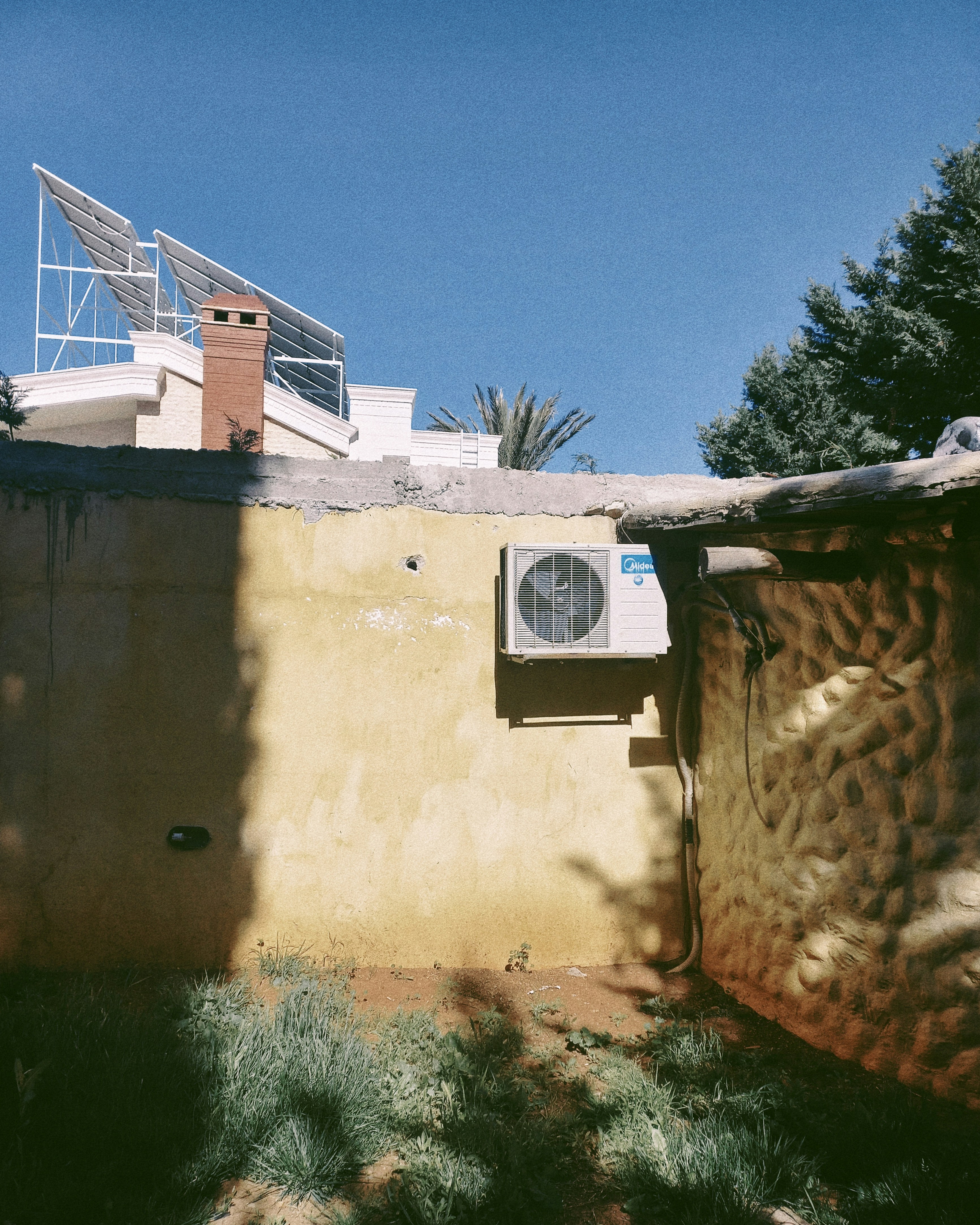 Aire acondicionado en una pared amarilla con paneles solares.
