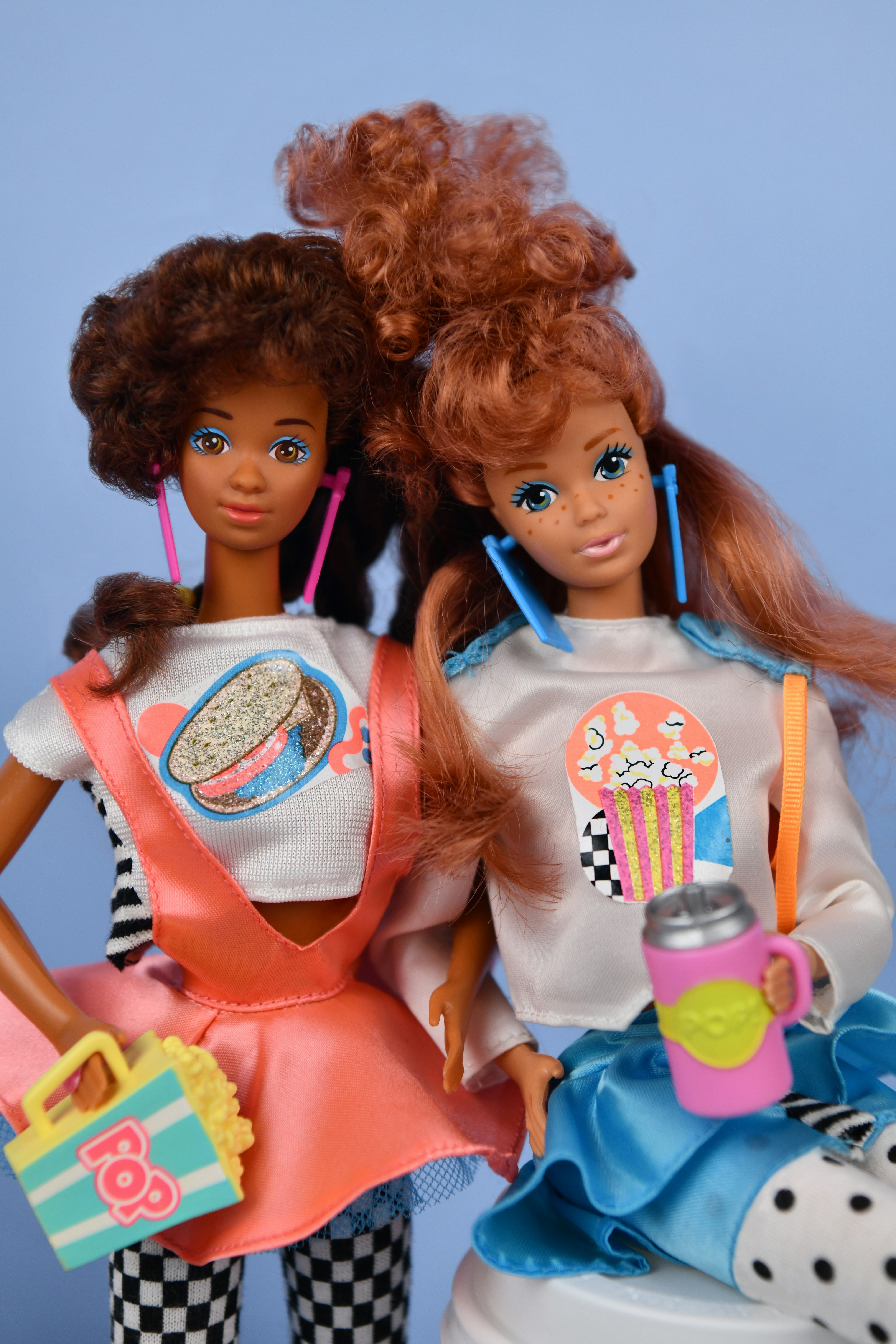 Two dolls in retro outfits holding snacks