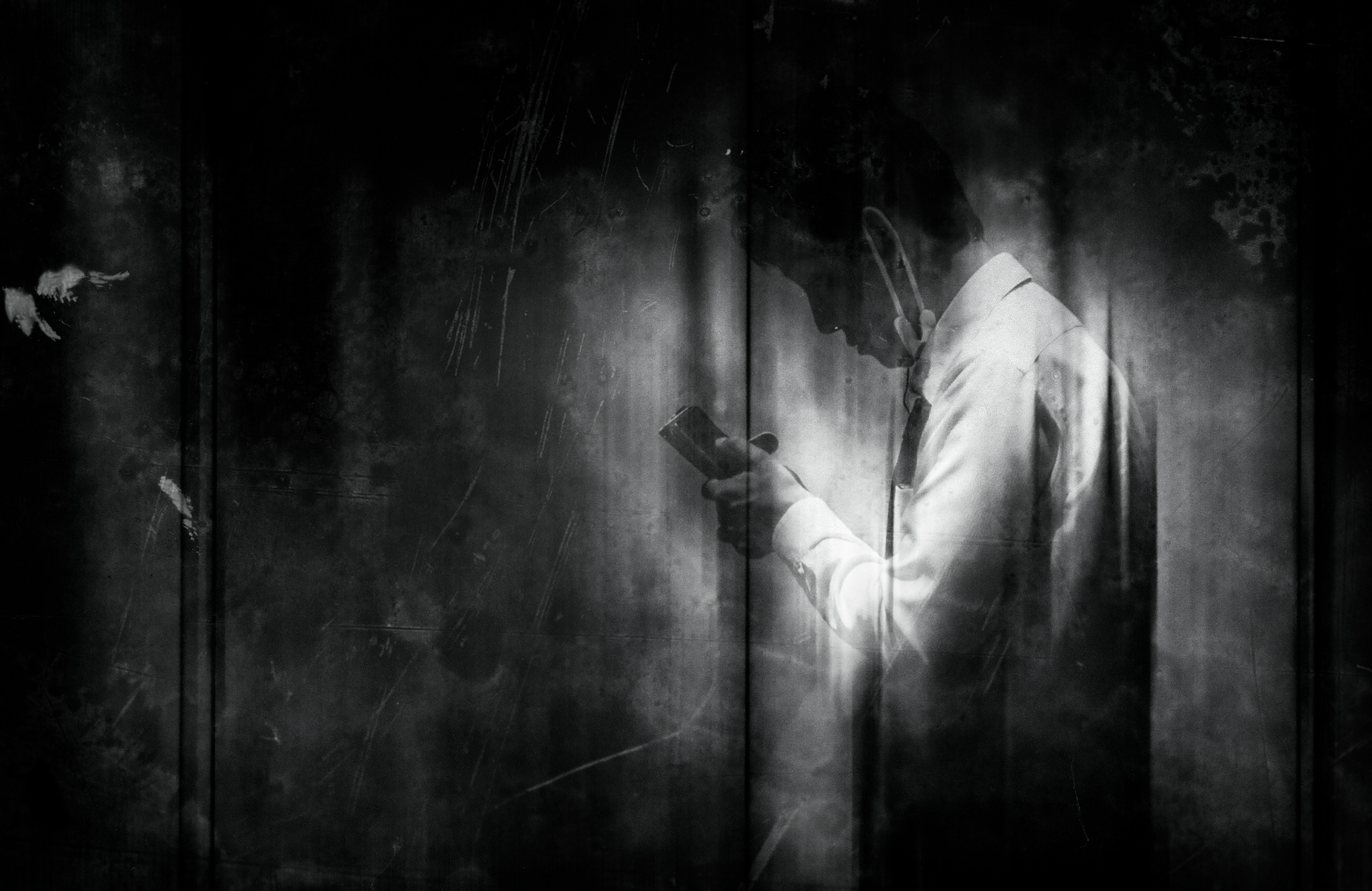 A ghostly figure in a white shirt stands in darkness