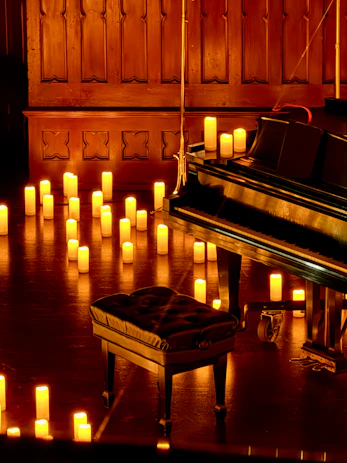 Grand piano and stool surrounded by glowing candles