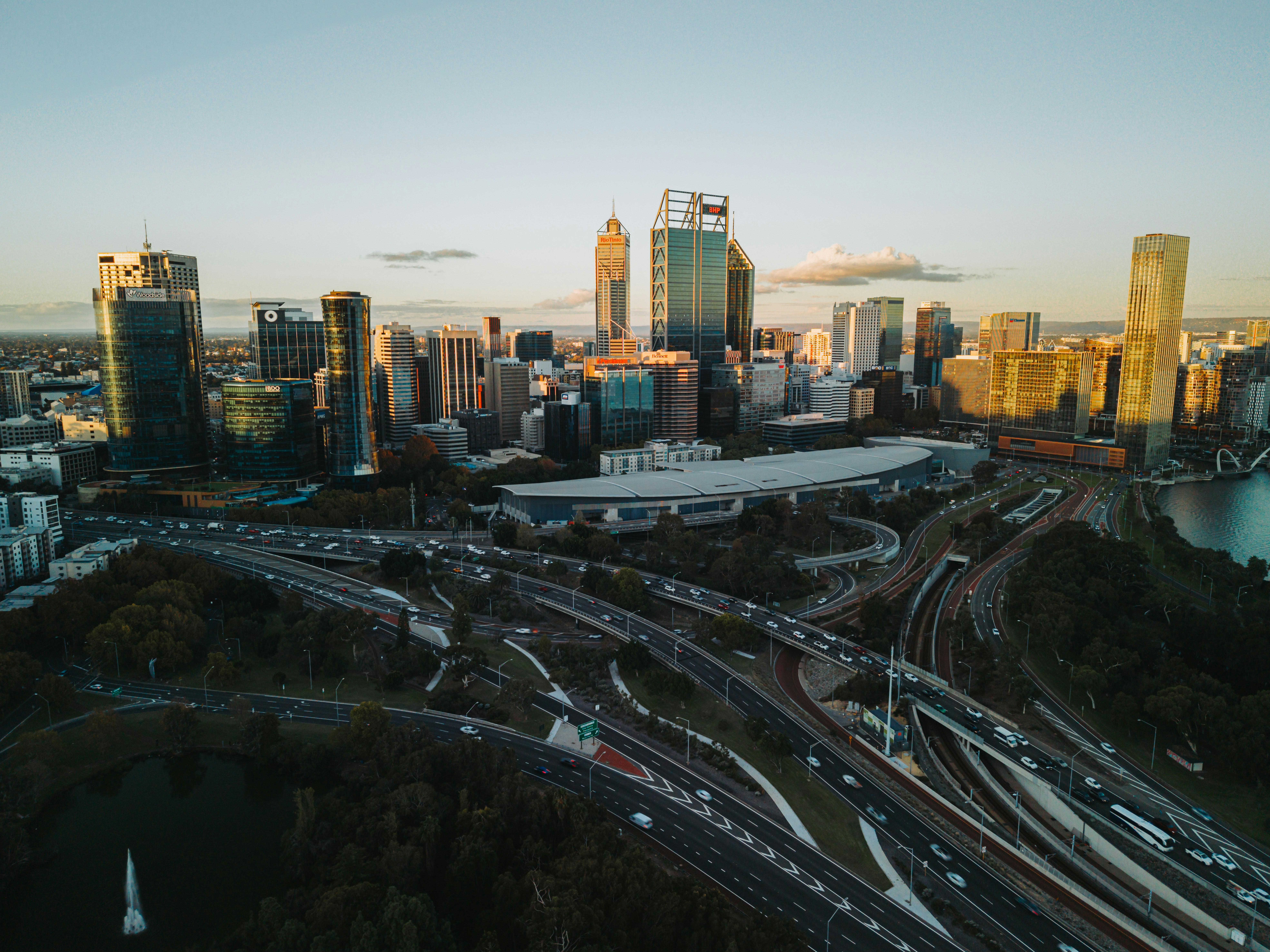 Modern cityscape with busy highway interchange at sunset.