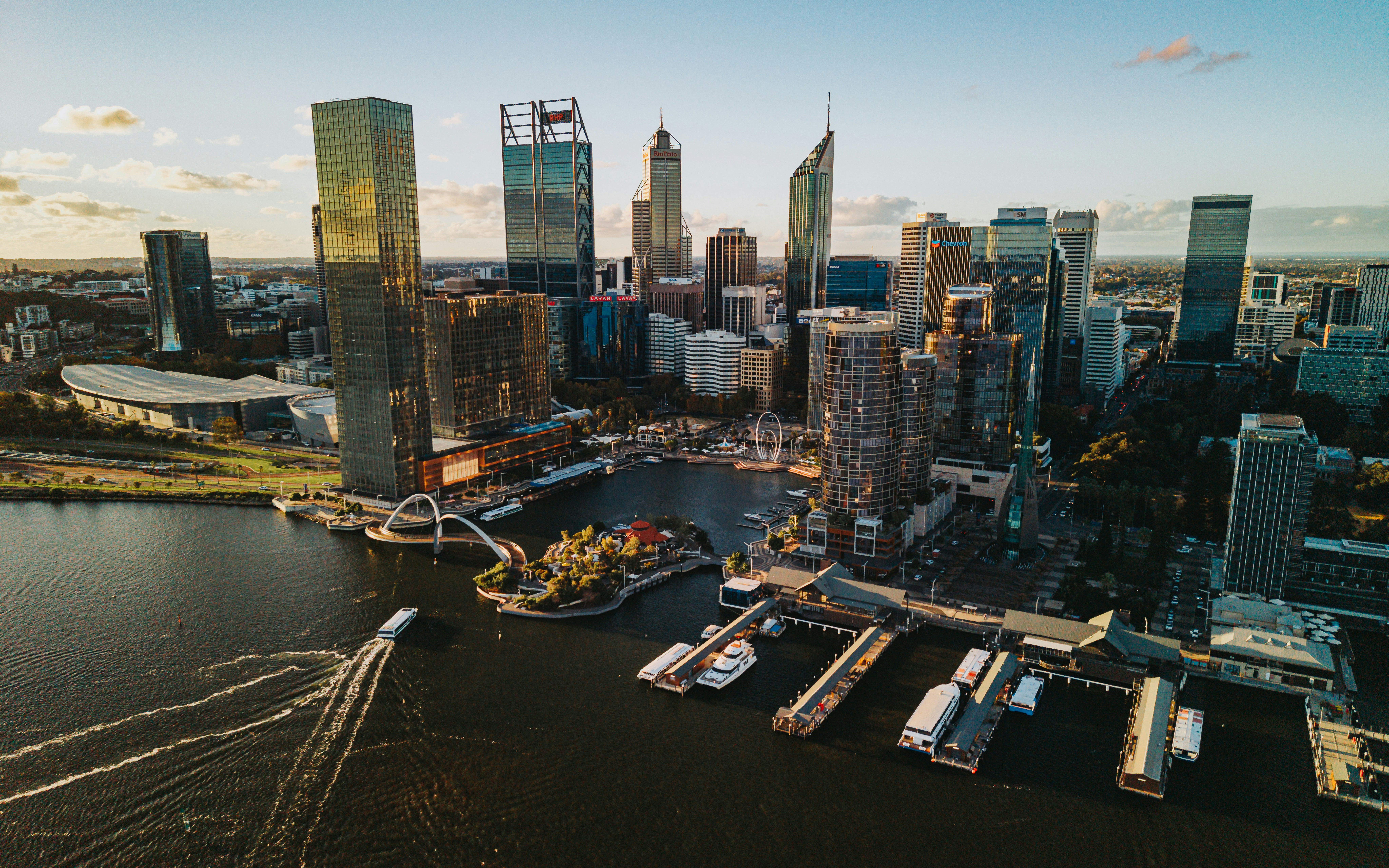 Modern cityscape with skyscrapers and a river at sunset