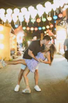 Couple kissing and dancing on a street at night.