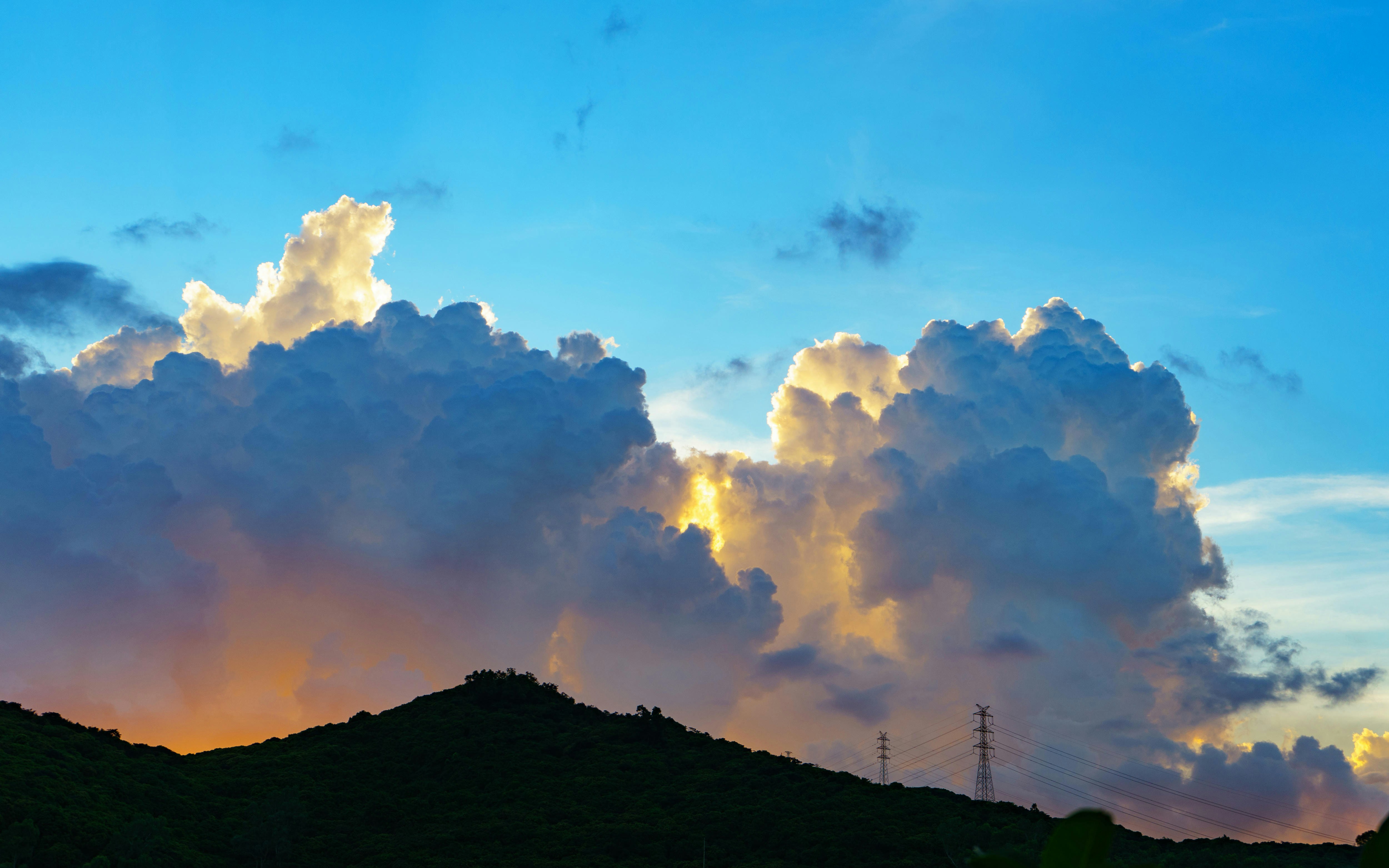 Dramatic clouds illuminated by sunset over dark hills