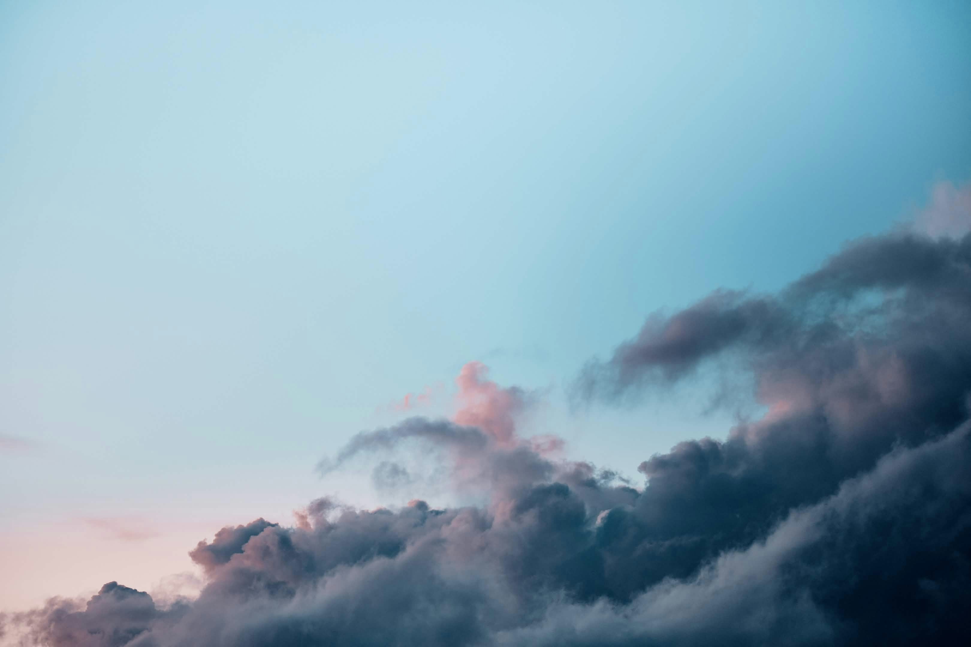 Dunkle Wolken ziehen über einen blassblauen Himmel.