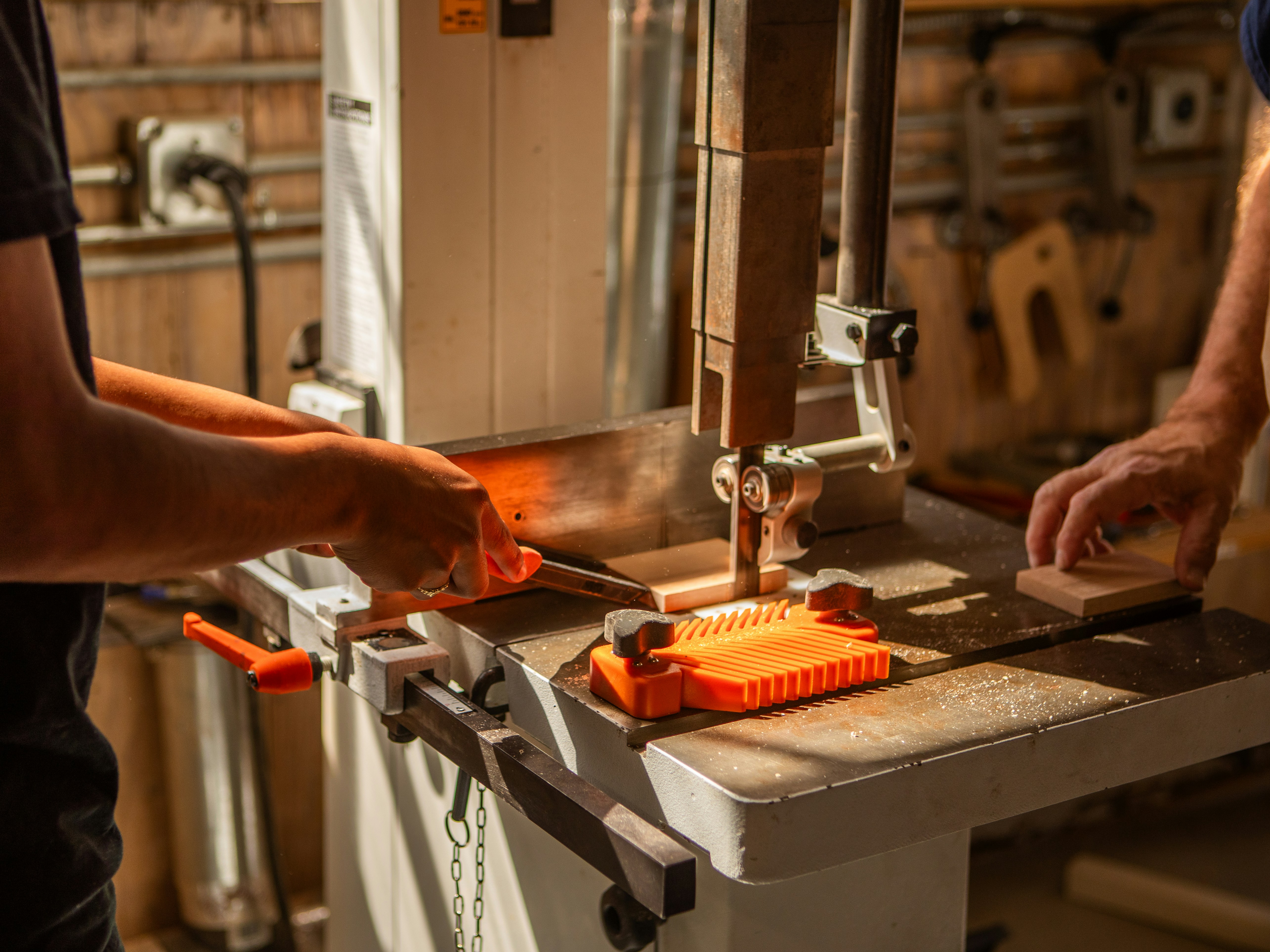 Two people using a band saw in a workshop