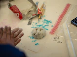 Hands shaping clay with sculpting tools and supplies.
