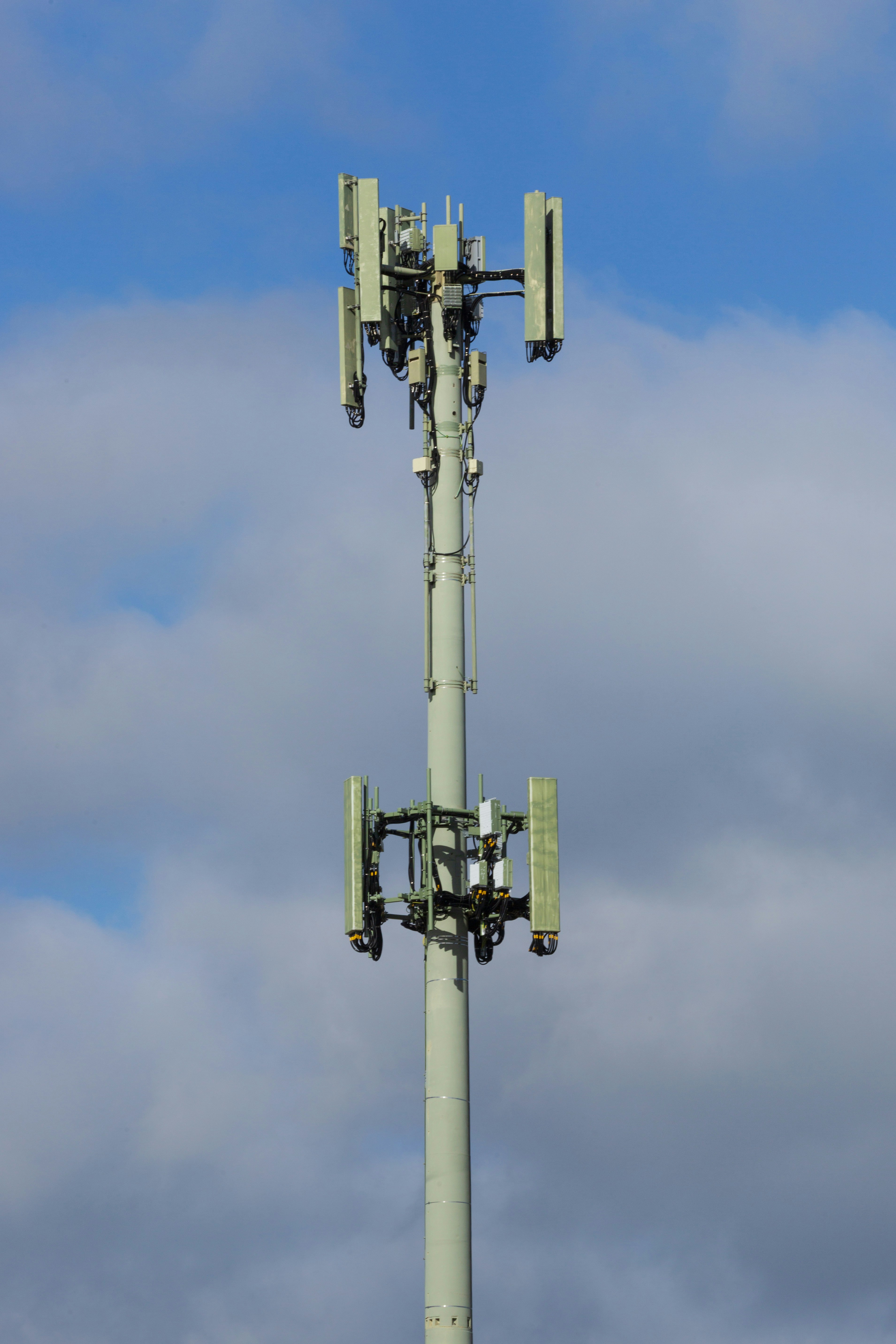 Cell tower with antennas against a cloudy sky