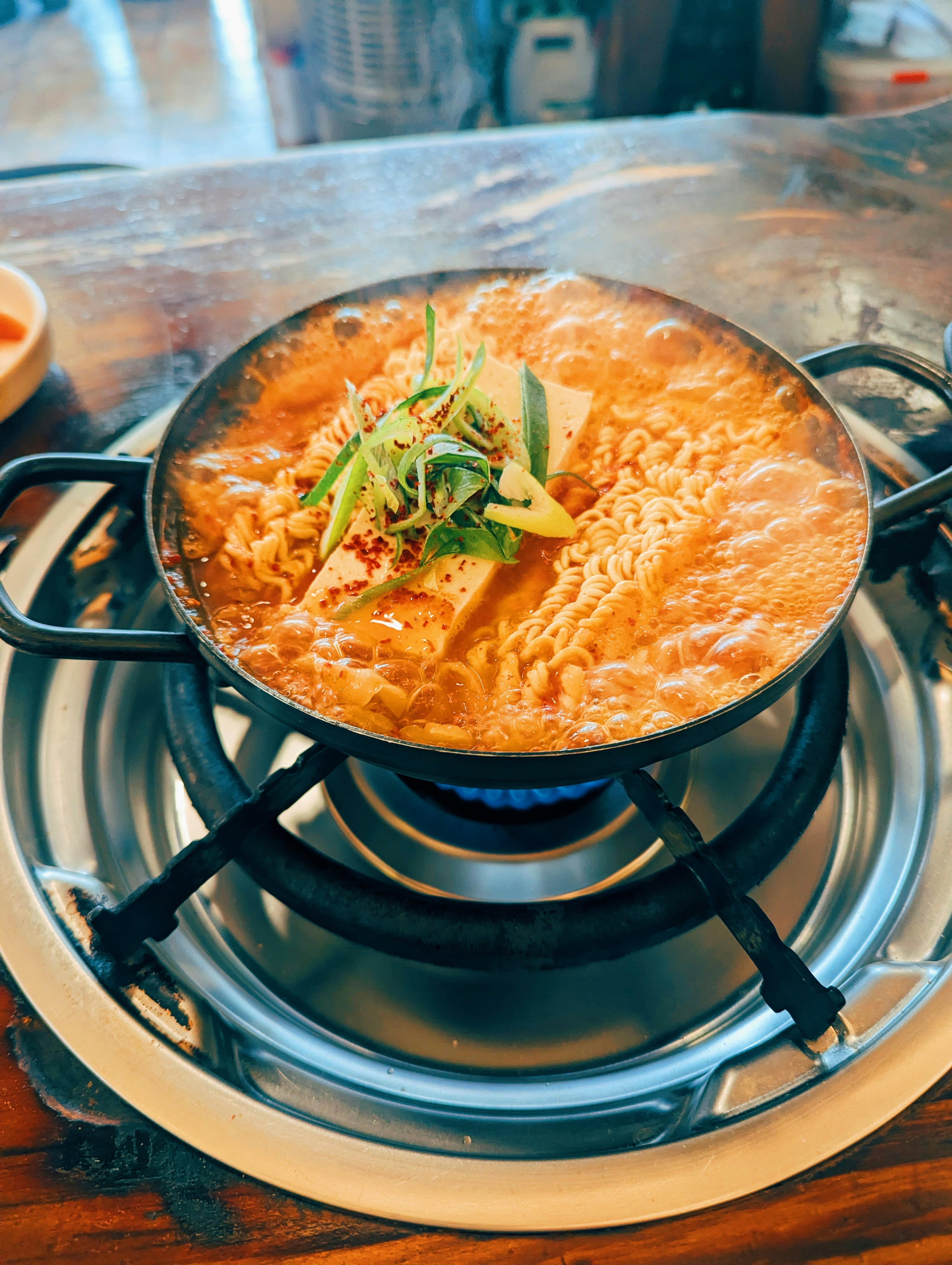 Panci rebusan korea yang menggelegak dengan mie dan tahu