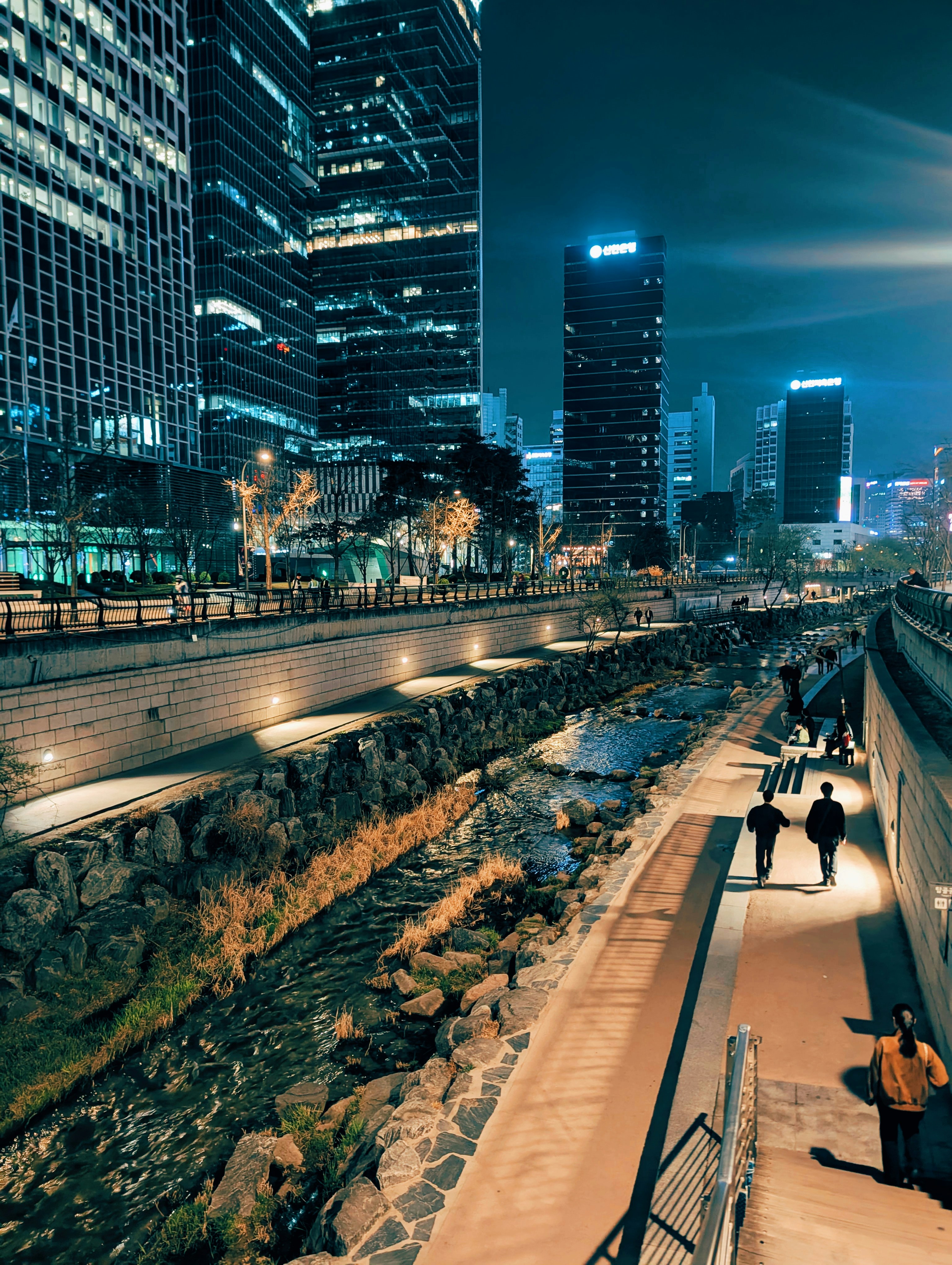 Pemandangan kota modern di malam hari dengan bangunan yang diterangi dan sungai.