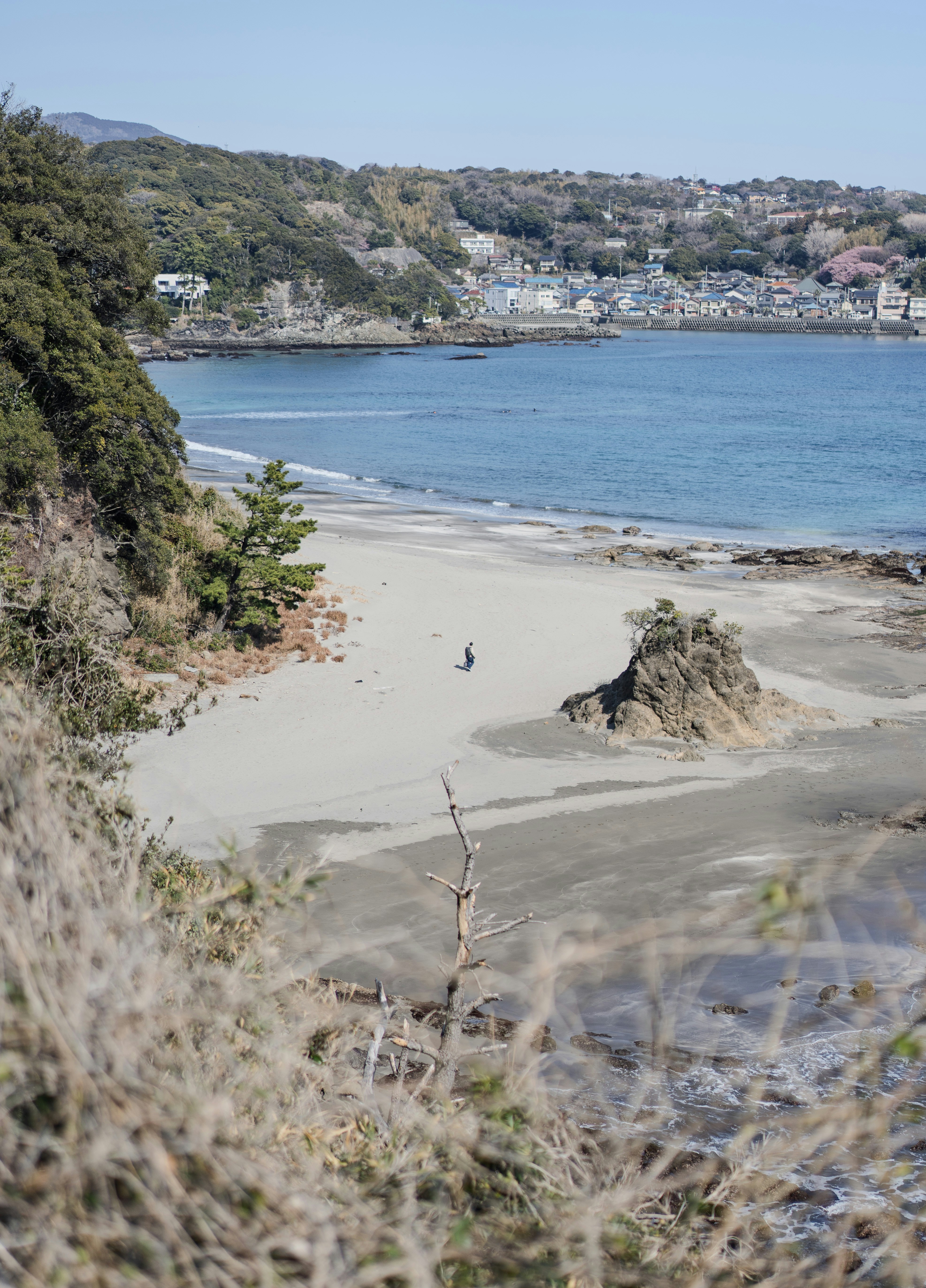 A person walks on a sandy beach by the ocean.