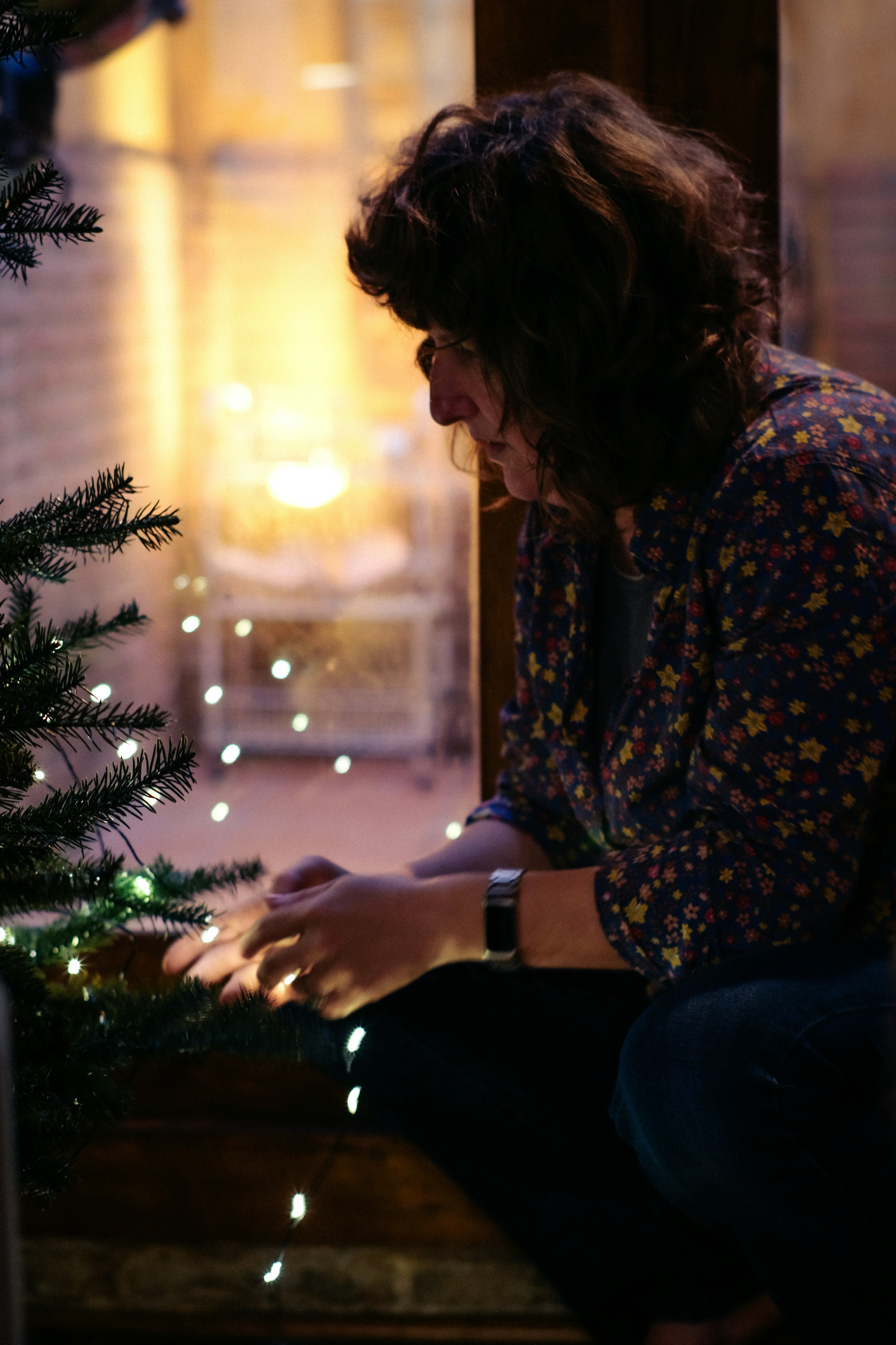 小さなクリスマスツリーにライトを飾る女性